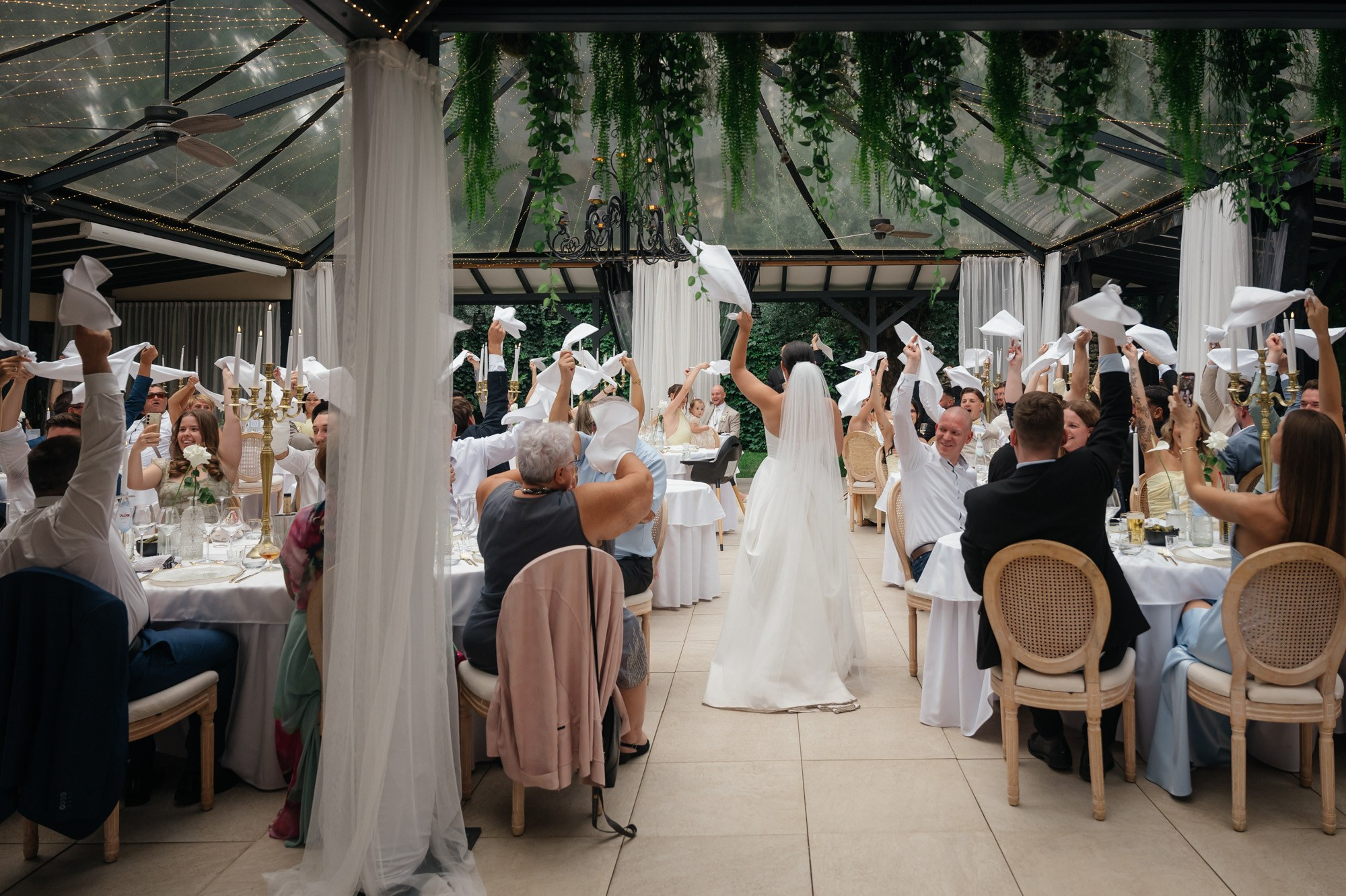 Couple entering the dining hall as guests wave white napkins