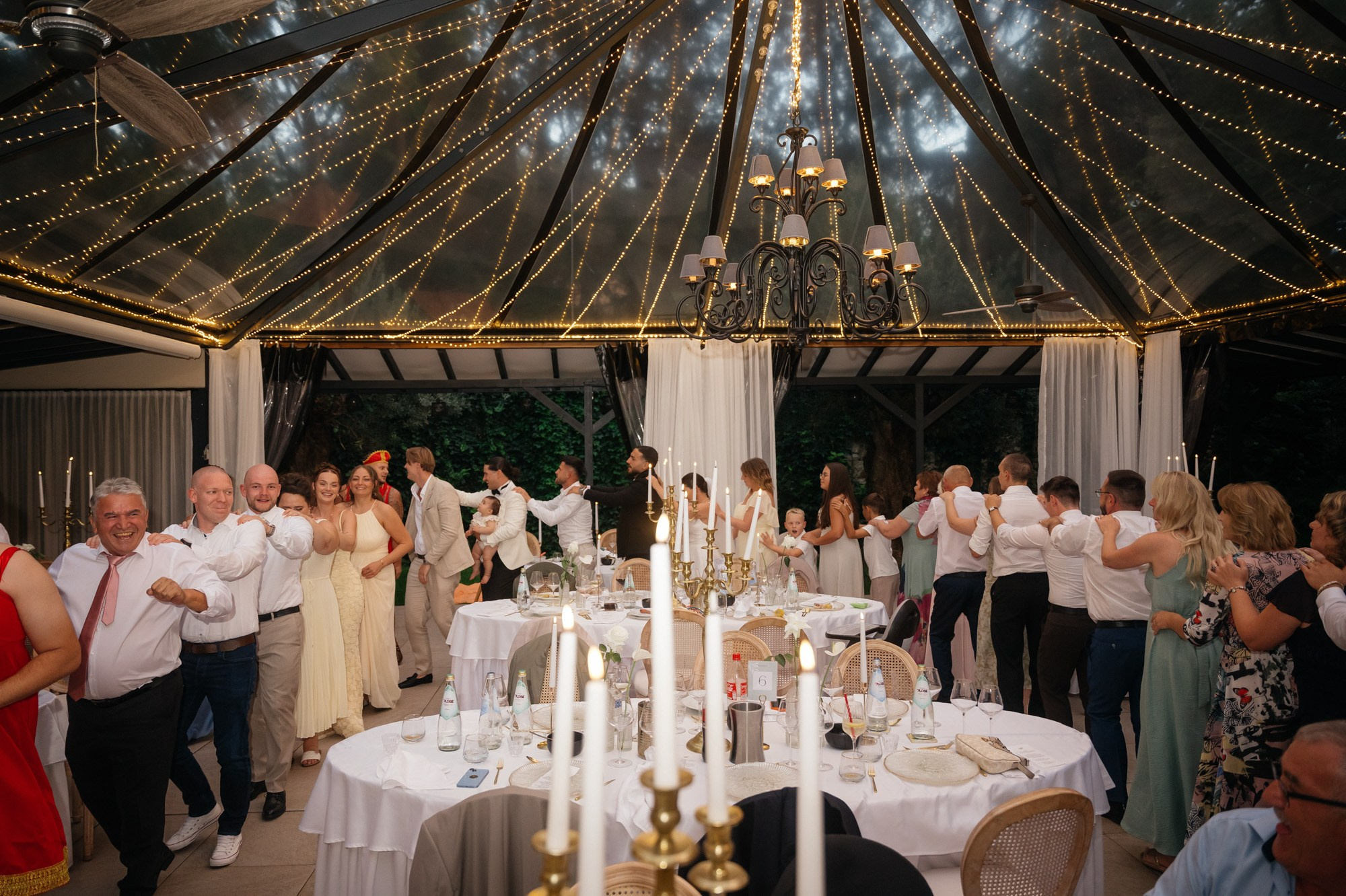 Guests celebrating between the tables in the glass pavilion