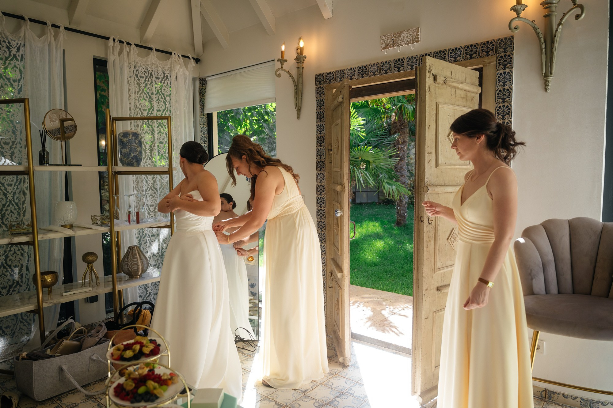 Bridesmaids helping the bride into her wedding dress