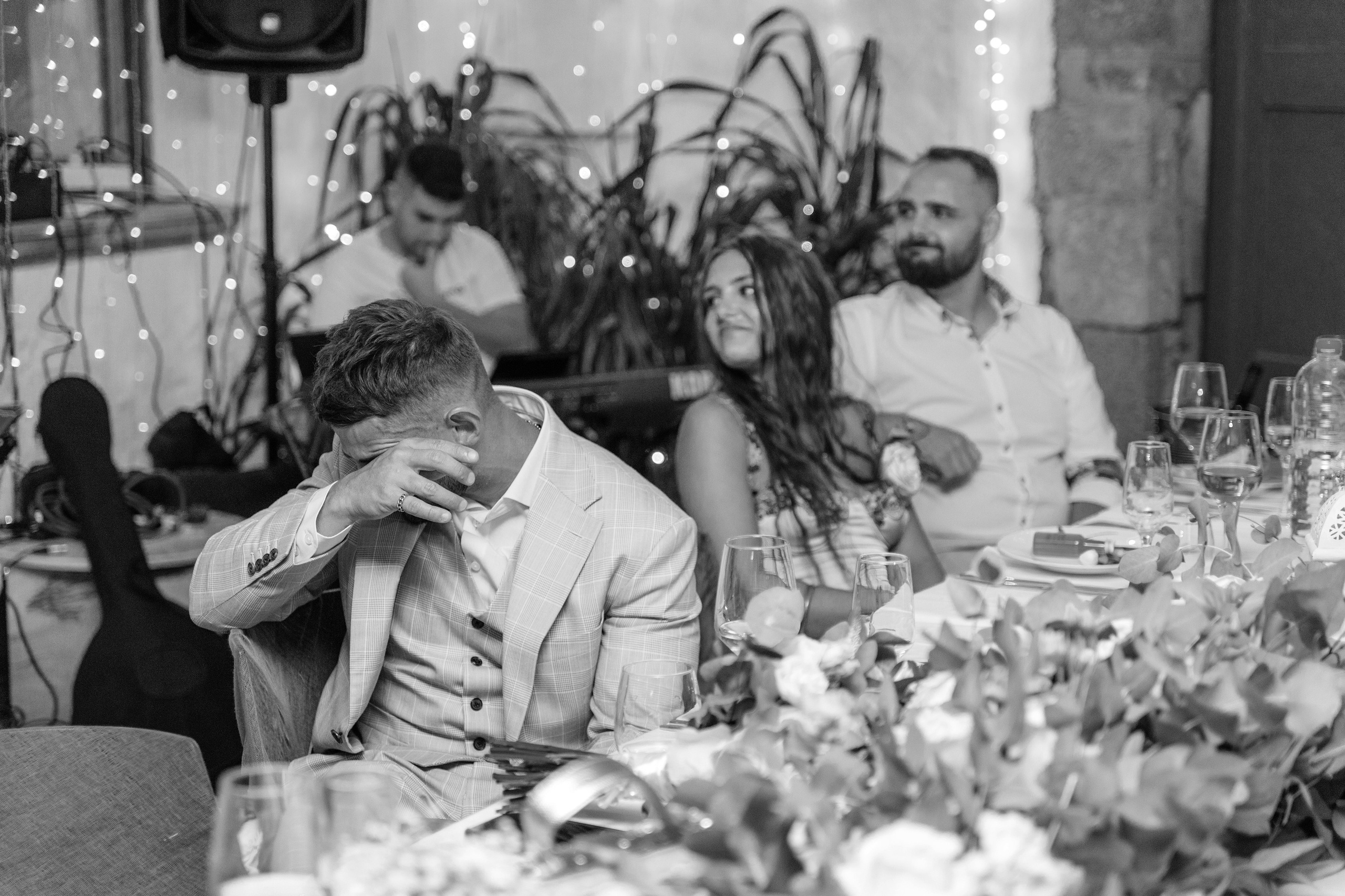 Candid moment of the groom wiping away his tears during a heartfelt wedding speech at a traditional Greek restaurant in Lindos, Greece, Rhodes.