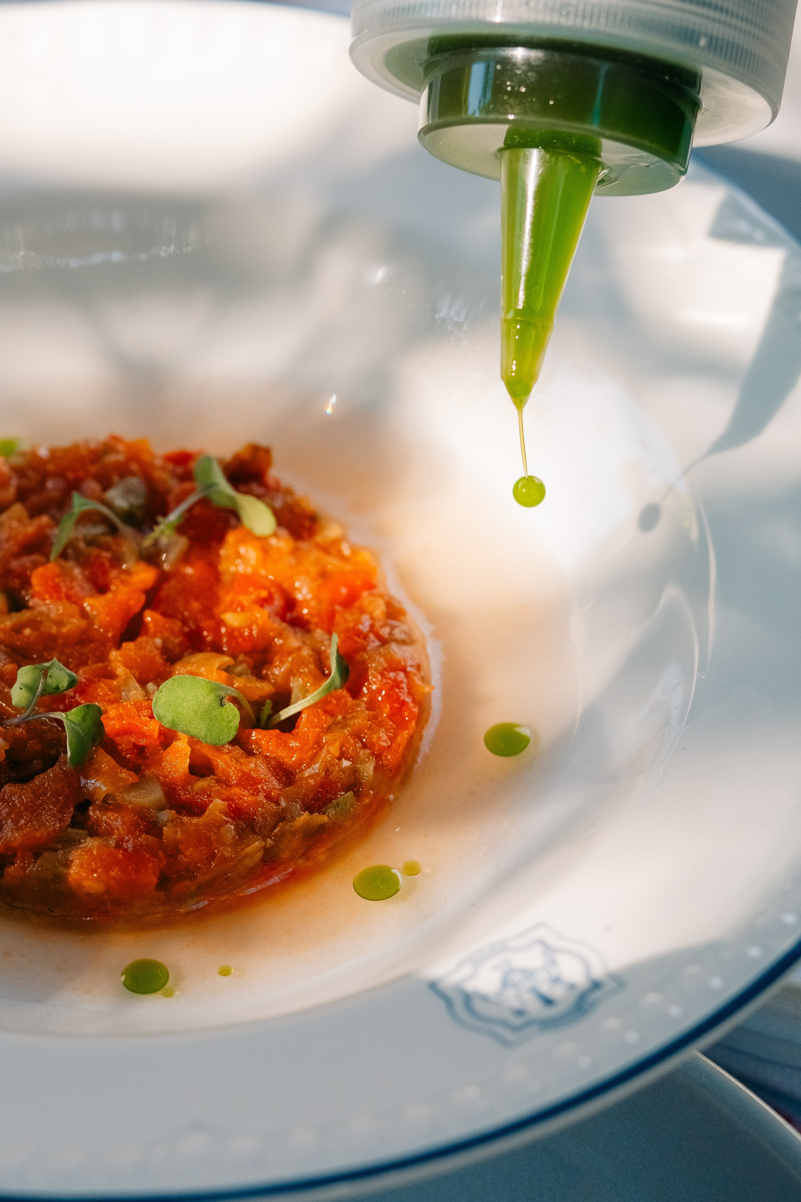 Крупный план гурме-тартара из овощей с зеленым маслом. Крупный план тартара из овощей, украшенного зеленым маслом из бутылочки.