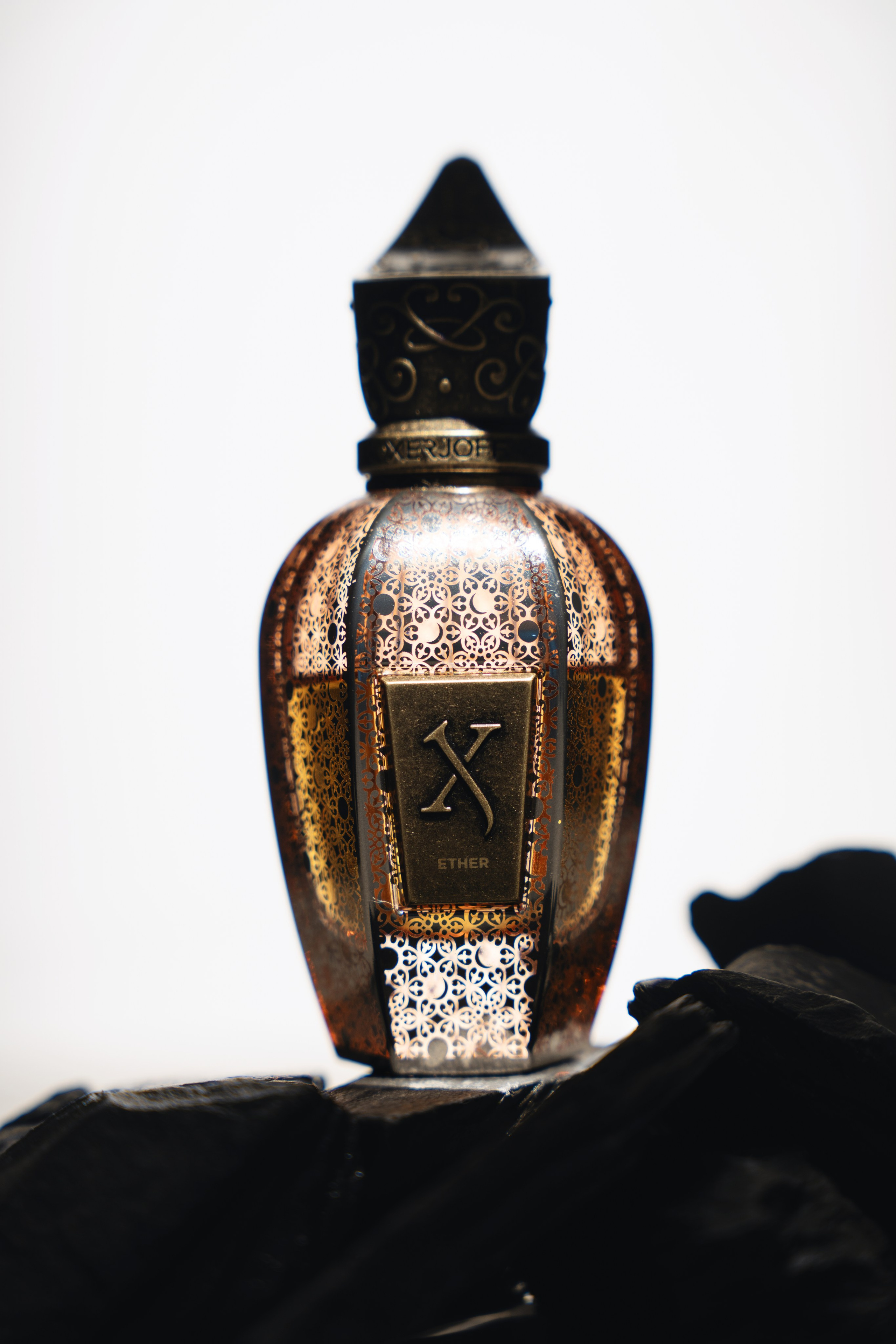 Luxury fragrance bottle reflection on black surface — minimal cinematic still life.