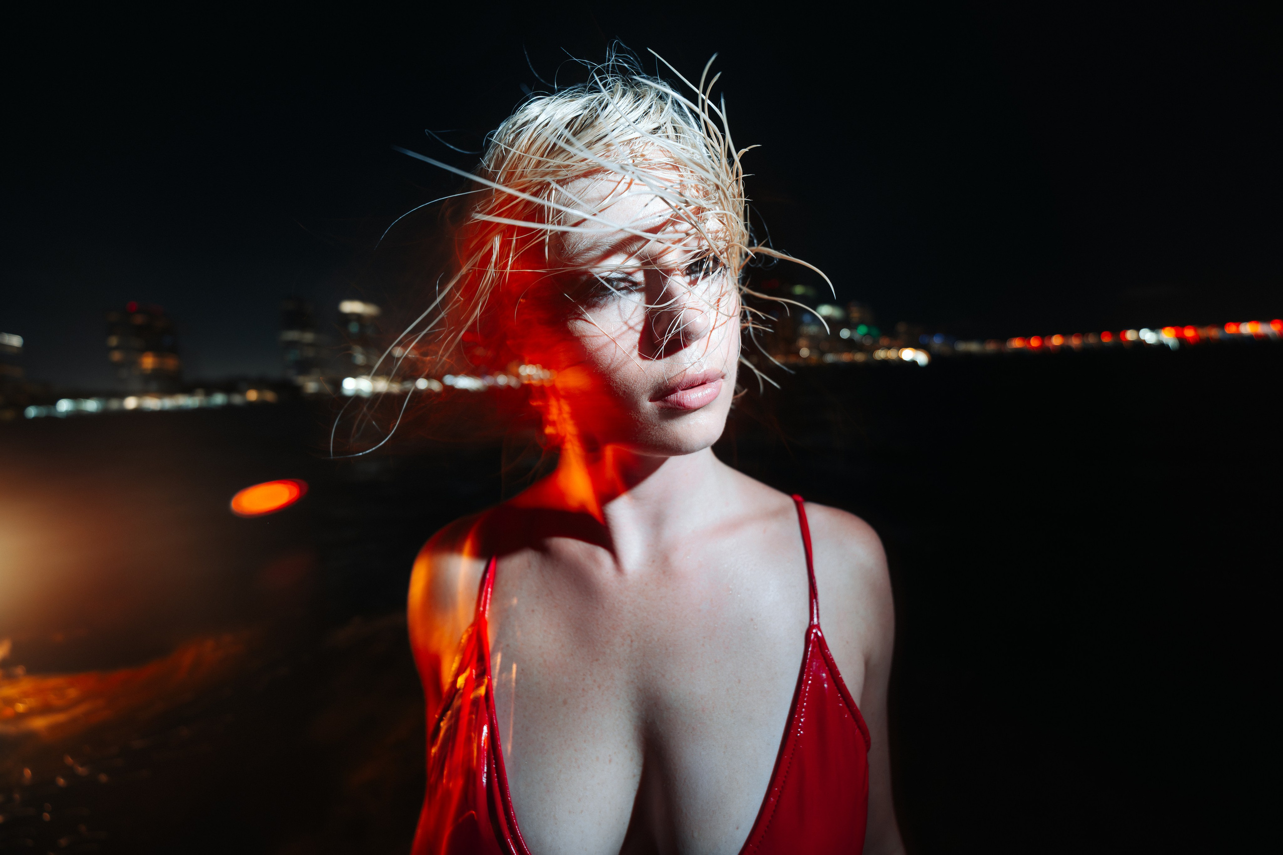 The model turns in motion, light tracing across the flowing dress while water reflects downtown lights. Atmospheric cinematic-style shoot focused on energy and presence. Top Miami photographer, night editorial mood.