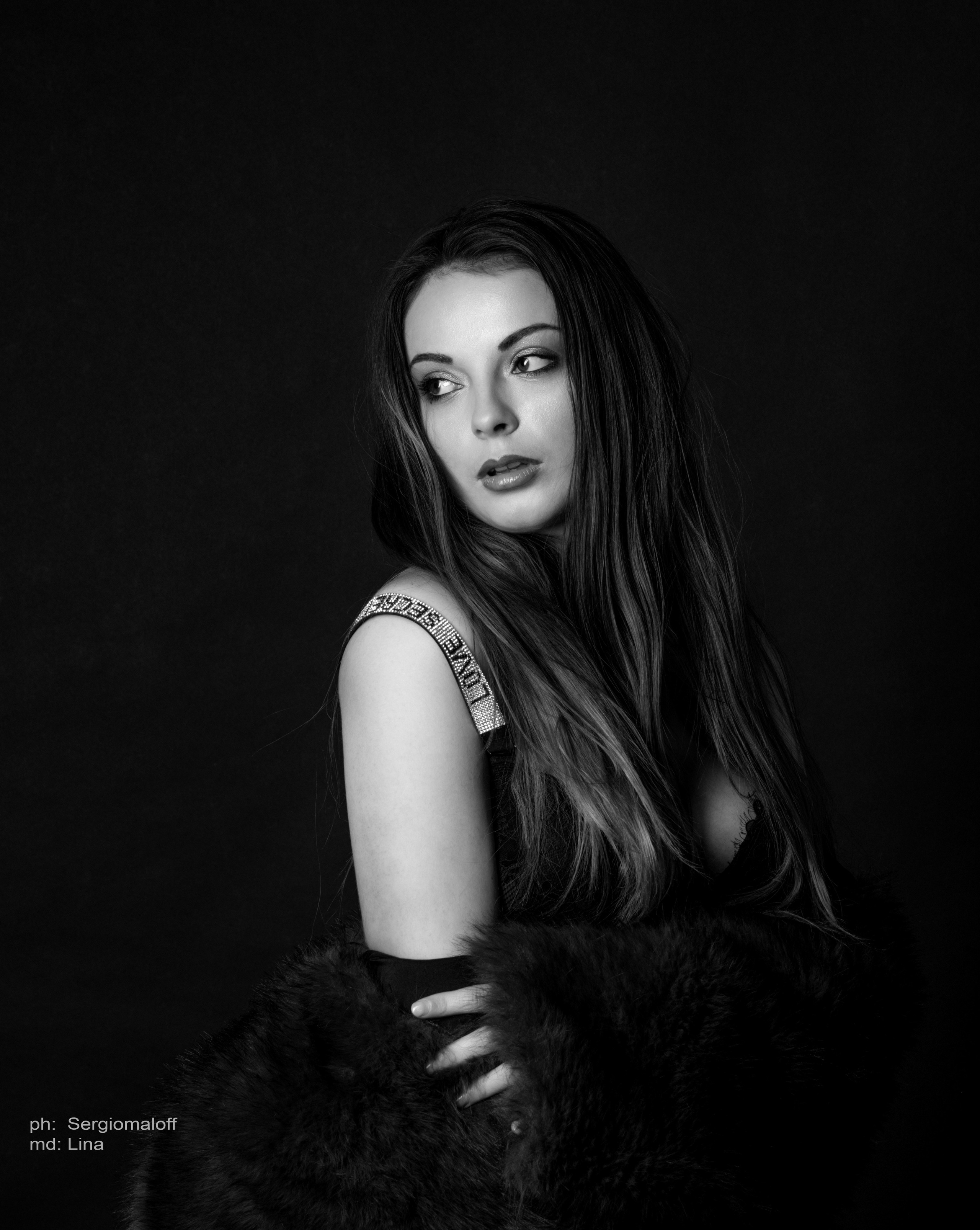Artistic black and white studio portrait of a woman in a striped blazer demonstrating professional lighting techniques.
