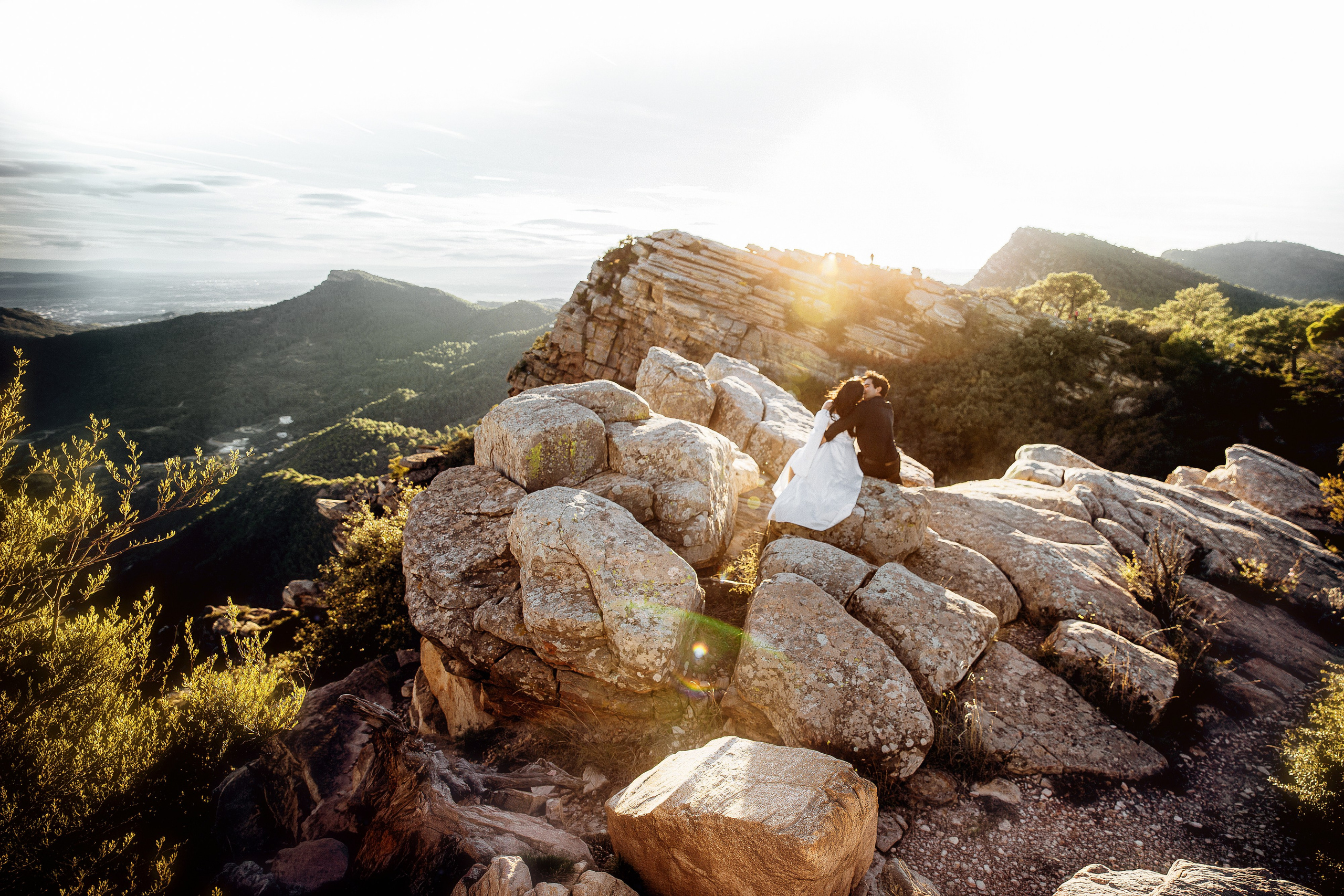 Sunlit rocky mountain landscape serving as a dramatic backdrop for a destination elopement in Barcelona, Spain. This panoramic view highlights the adventurous setting of an intimate wedding or mountain proposal.