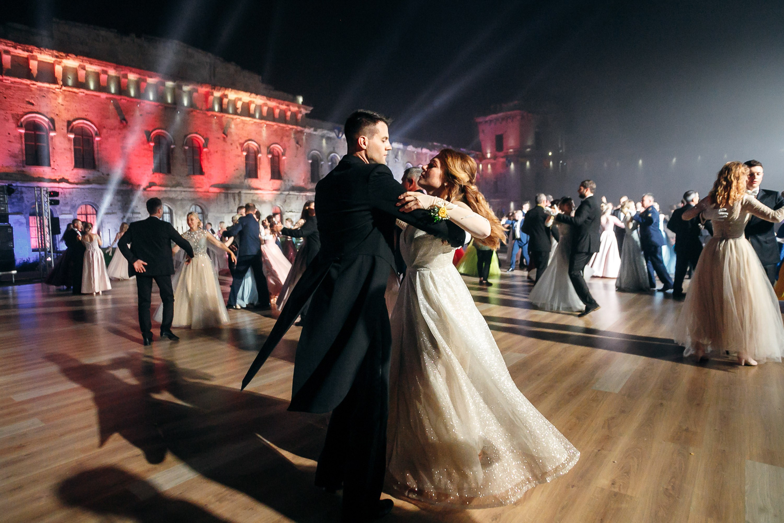 Dancing couples at an outdoor ball near an illuminated building