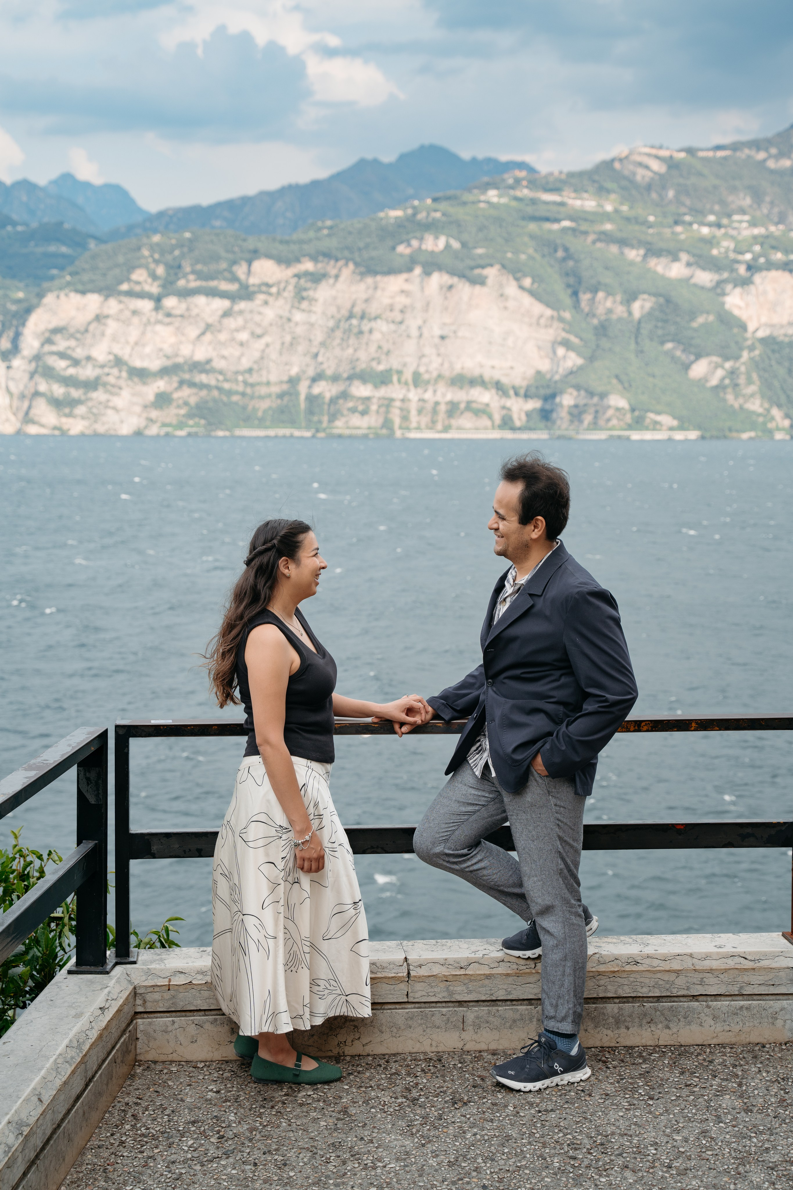 Man proposing to his partner by the water in Malcesine with Lake Garda and mountains behind.