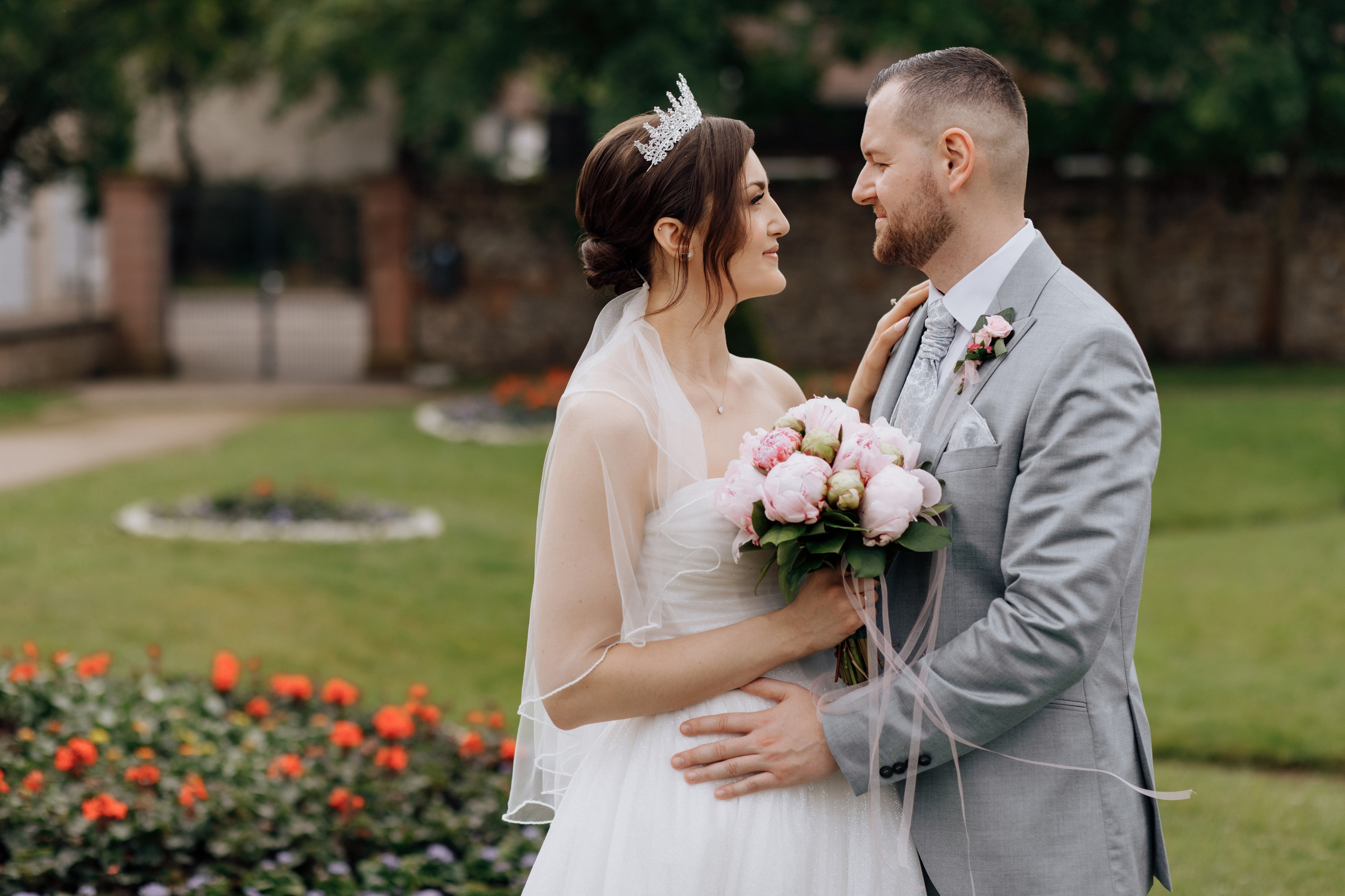 Der Bräutigam und die Braut schauen sich verliebt an, während sie vor dem schönen Garten stehen.