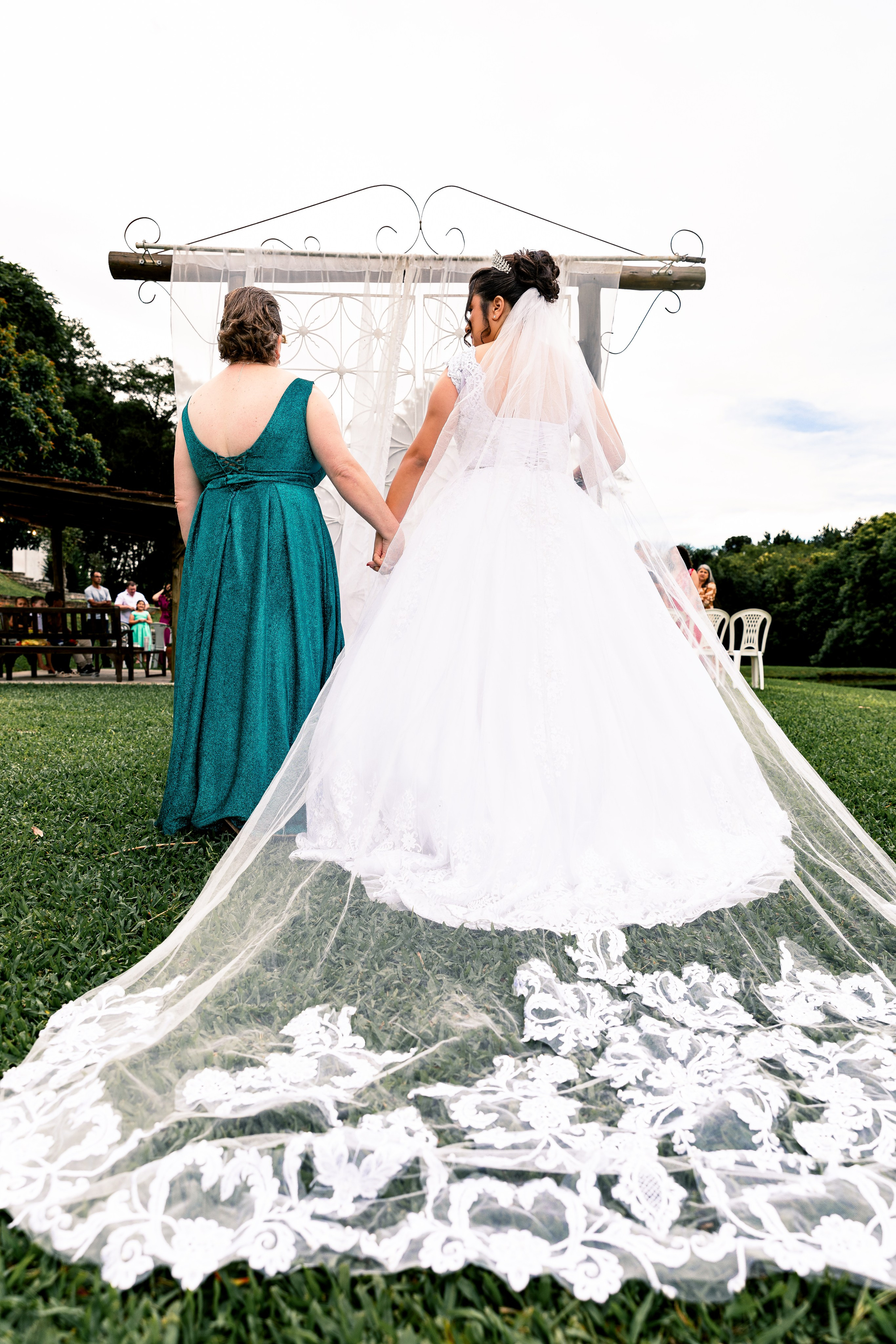 Noiva e mãe de mãos dadas na entrada do altar, união e apoio materno no início da cerimônia.