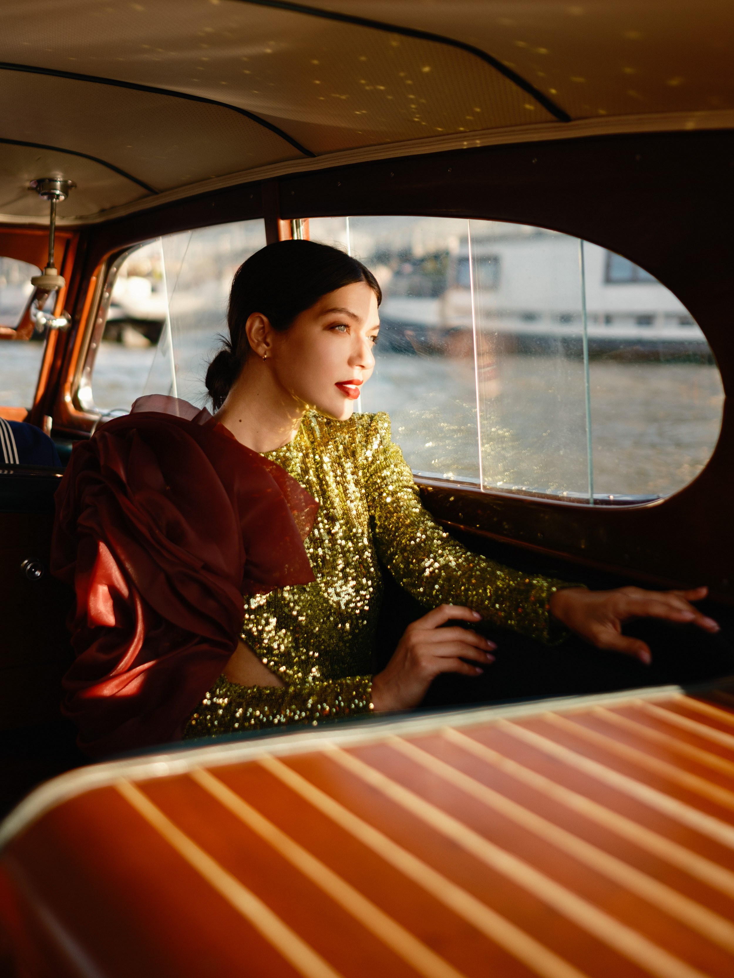 Luxury editorial photography of a sequin gold dress inside a vintage wooden yacht in Paris