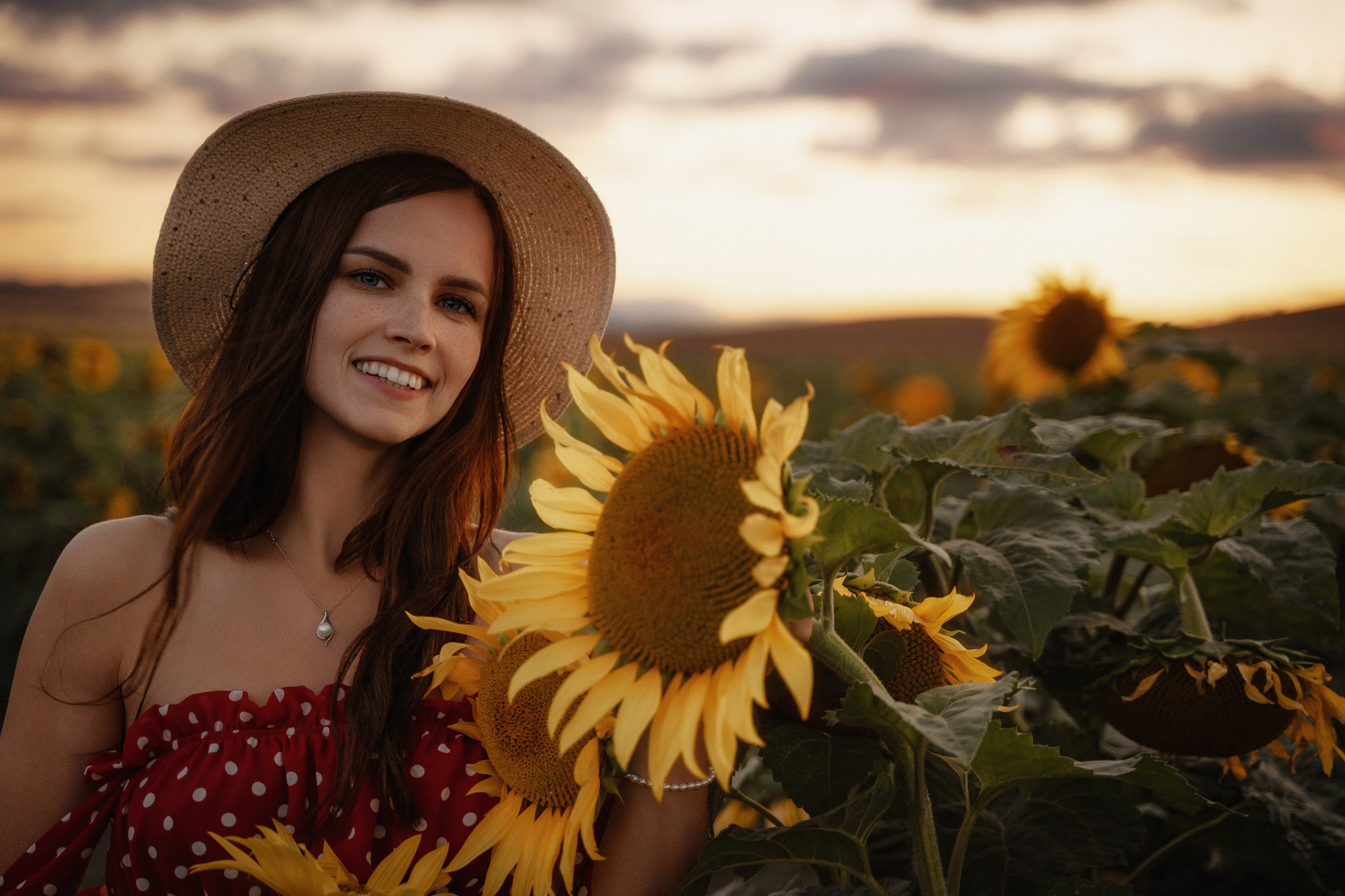 Portrait of a young woman in a sunflower field at sunset by Marbella-based photographer