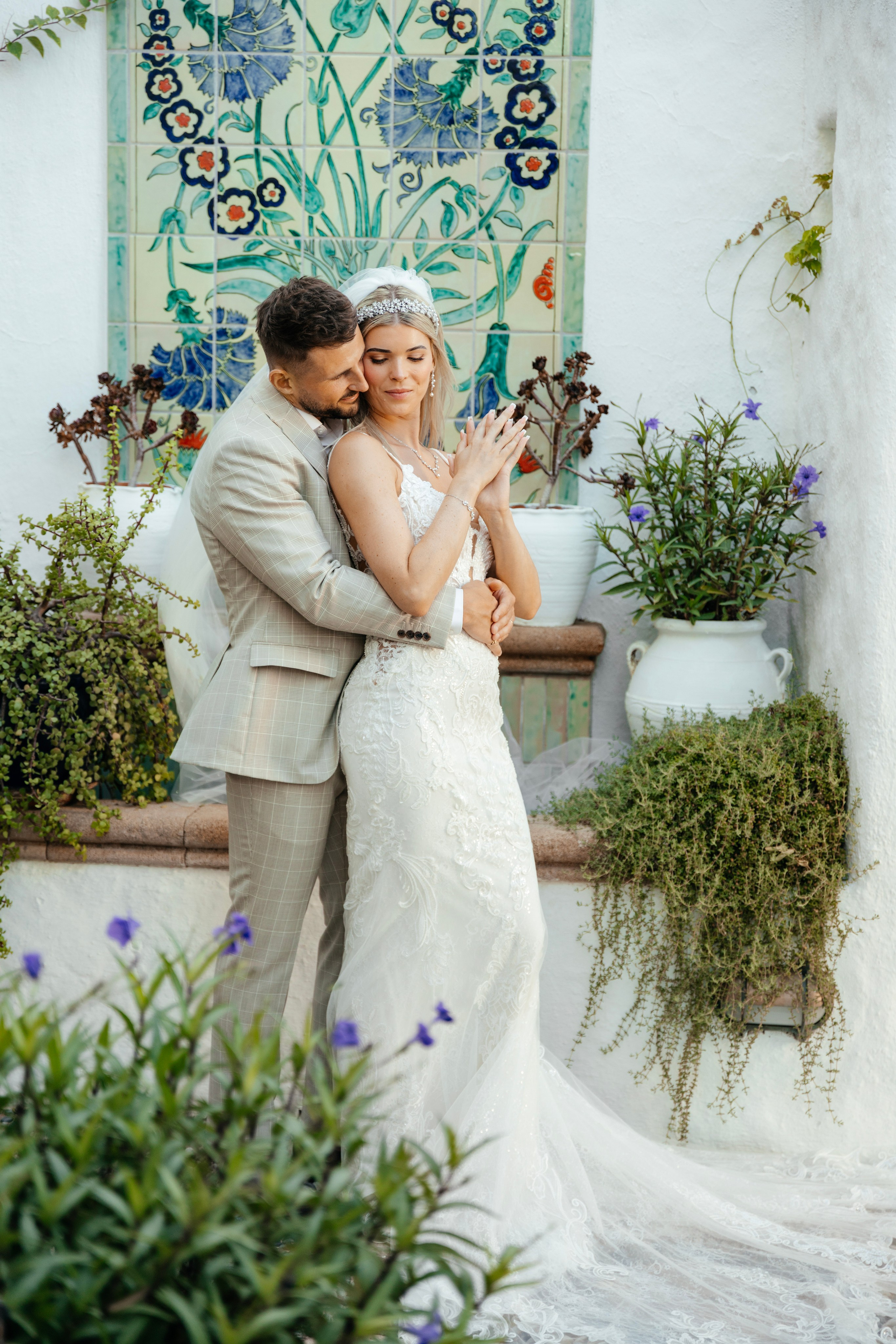 Bride and groom enjoying a quiet moment together on a cobblestone street in Lindos, with traditional Greek architecture around them