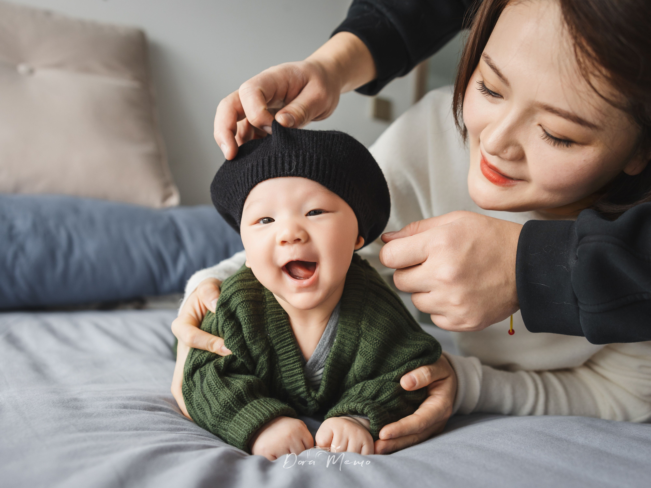 Smiling baby wearing black hat and green sweater, at-home baby photoshoot Shanghai