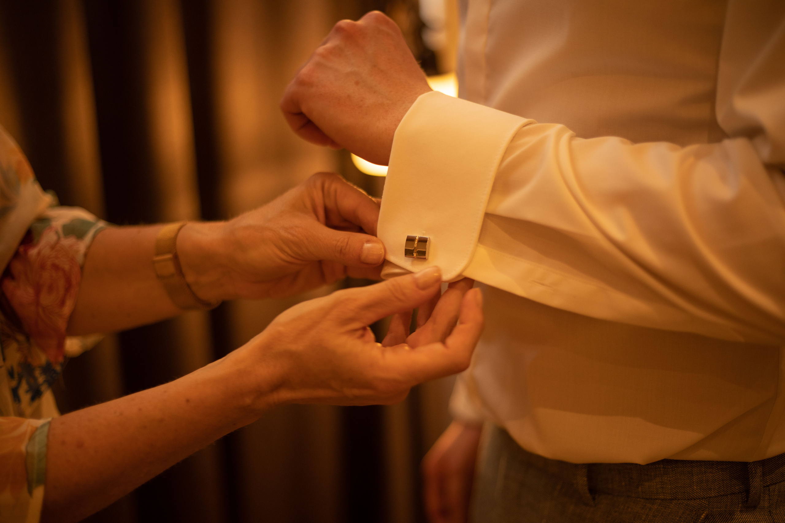 Die Mutter von dem Bräutigam macht sein Hemd zu