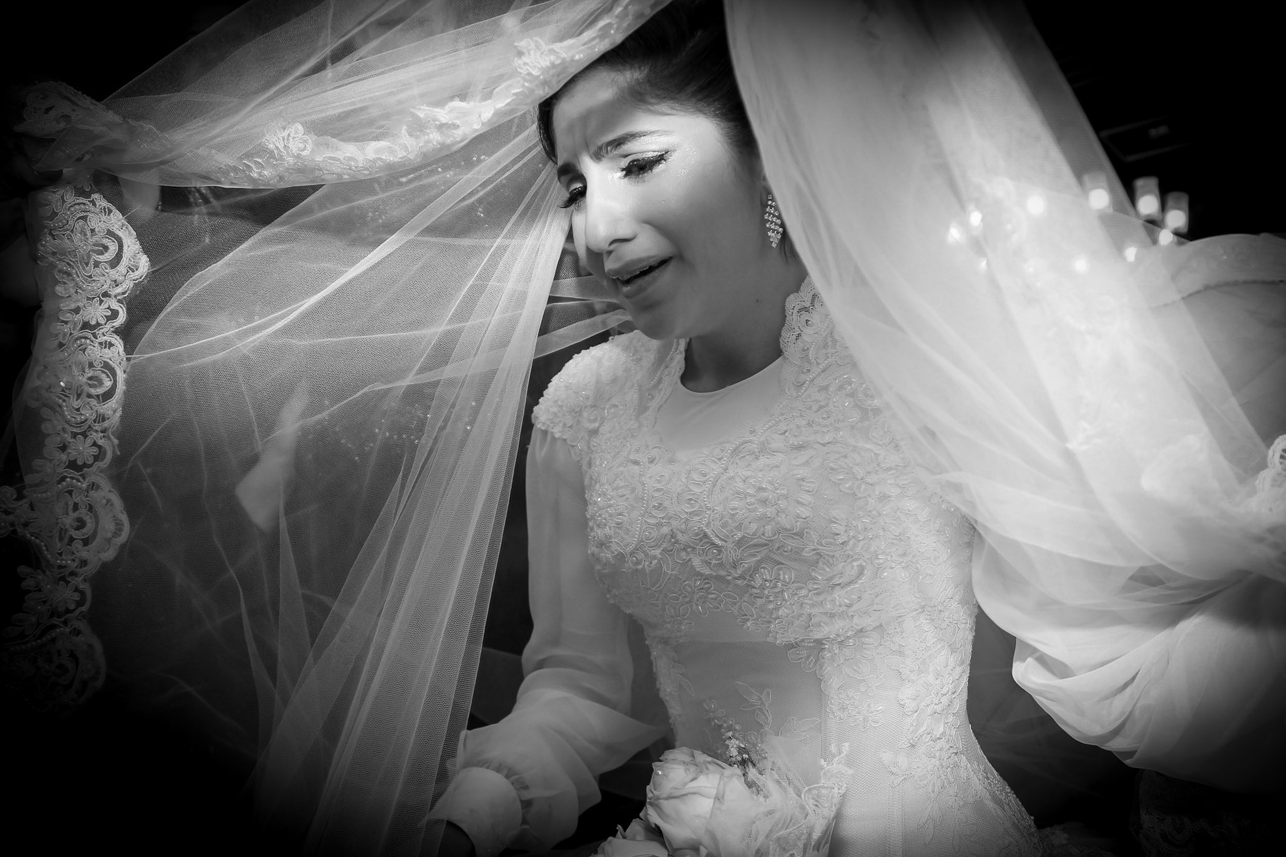 Emotional black and white portrait of a crying bride under her lace veil during a wedding in Israel