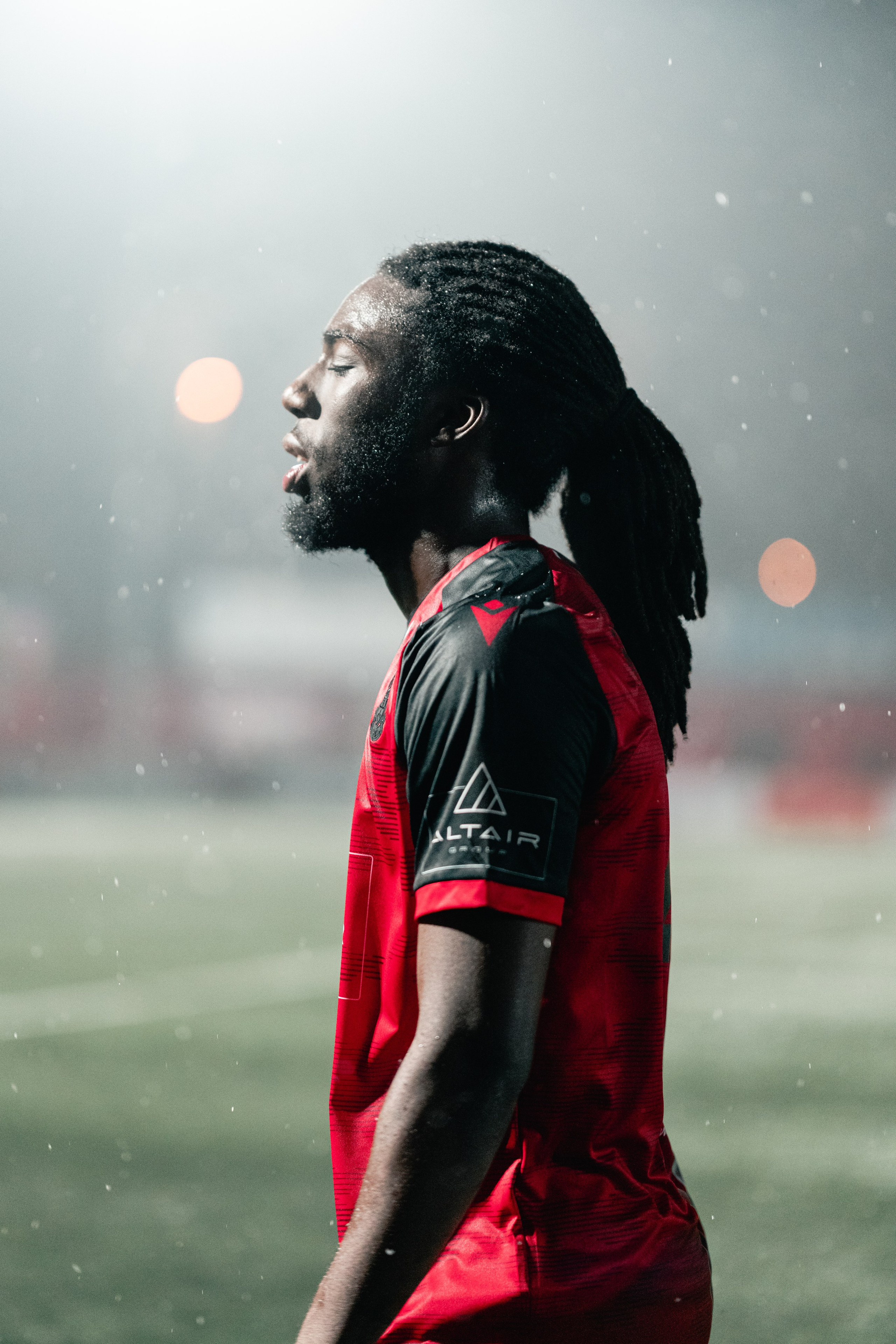 Michael Reindorf of Tamworth FC stands in profile in heavy rain under the floodlights during the Birmingham Senior Cup match at The Lamb Ground, Feb 3 2026.