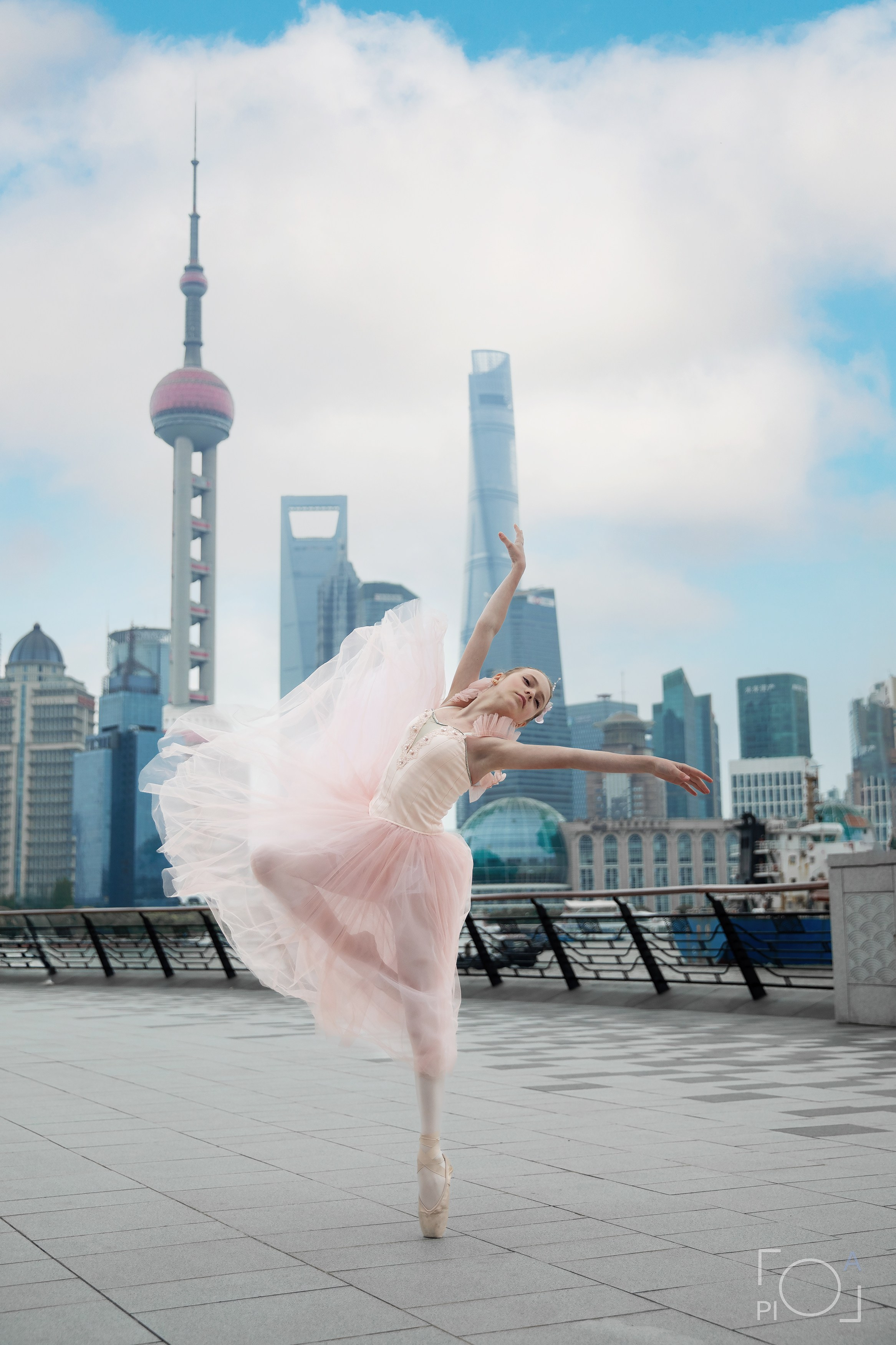 Young ballerina in pink tutu and pointe shoes on Shanghai waterfront. Airy romantic photo.