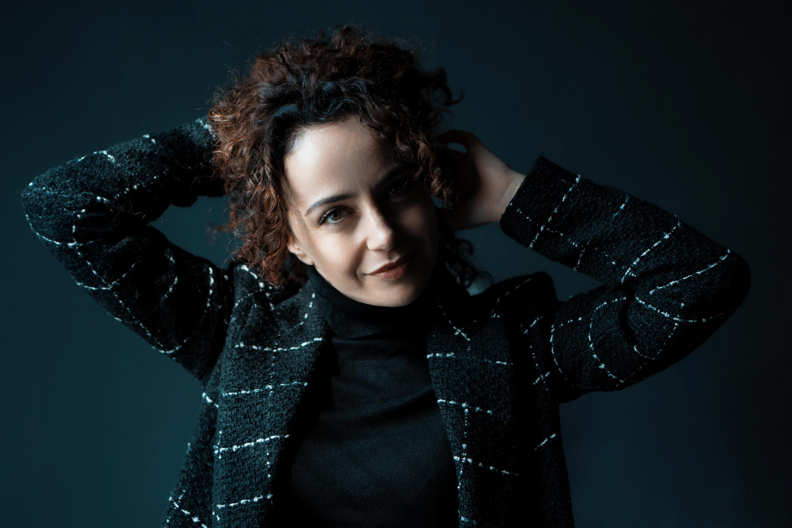 Studio-Portrait, junge Frau mit Locken, Hände im Nacken – künstlerische Portraitfotografie Dresden