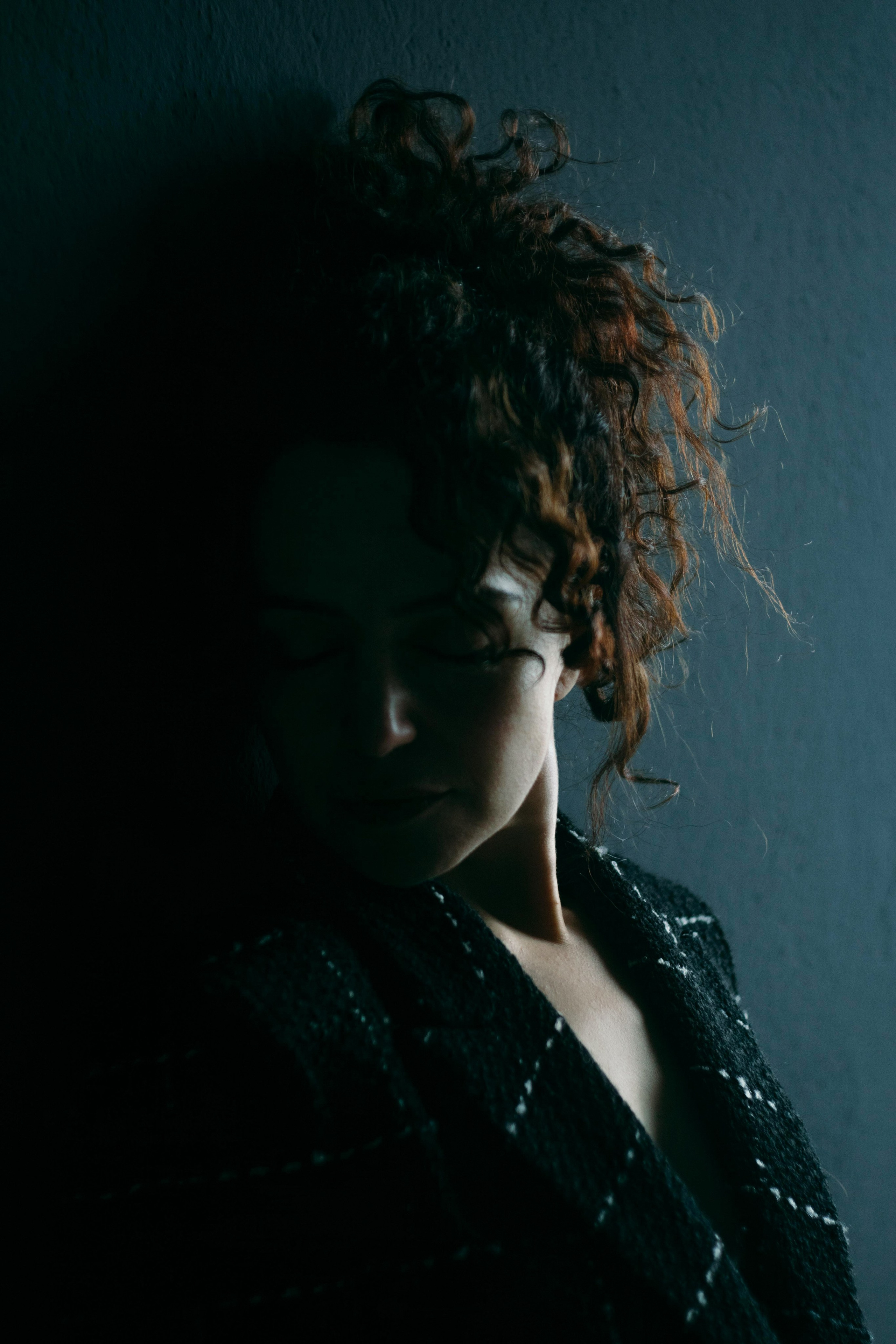 Stimmungsvolles Schwarzlicht-Portrait, Frau lehnt an Wand – künstlerische Fotografie