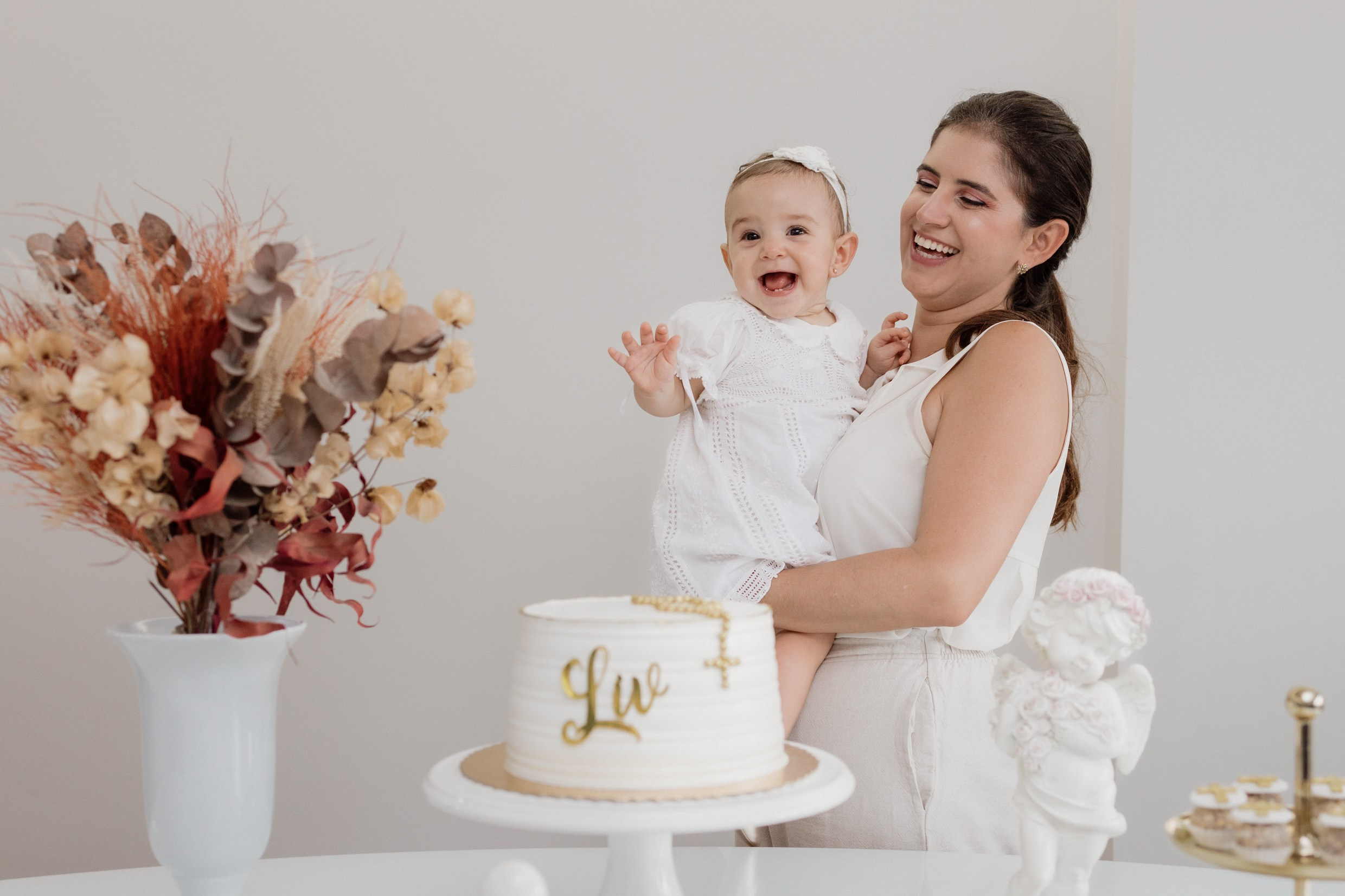 Mãe e filha sorrindo à mesa durante celebração de batizado