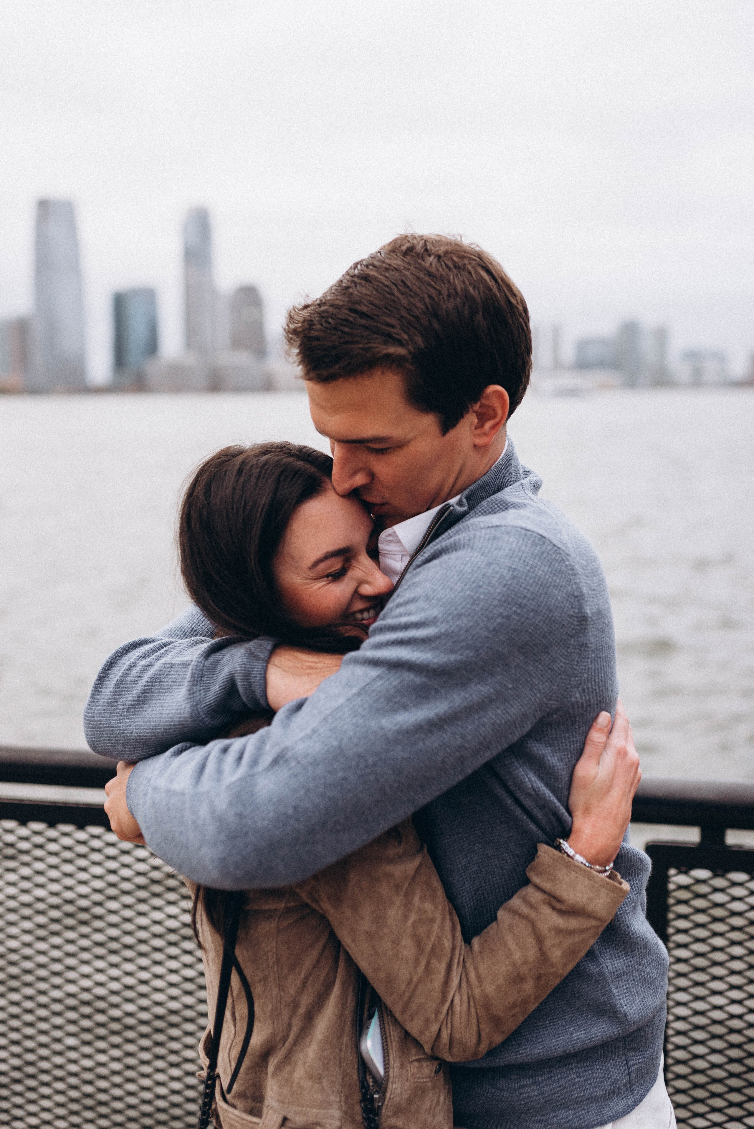 Couple smiling after engagement on Brooklyn Bridge.