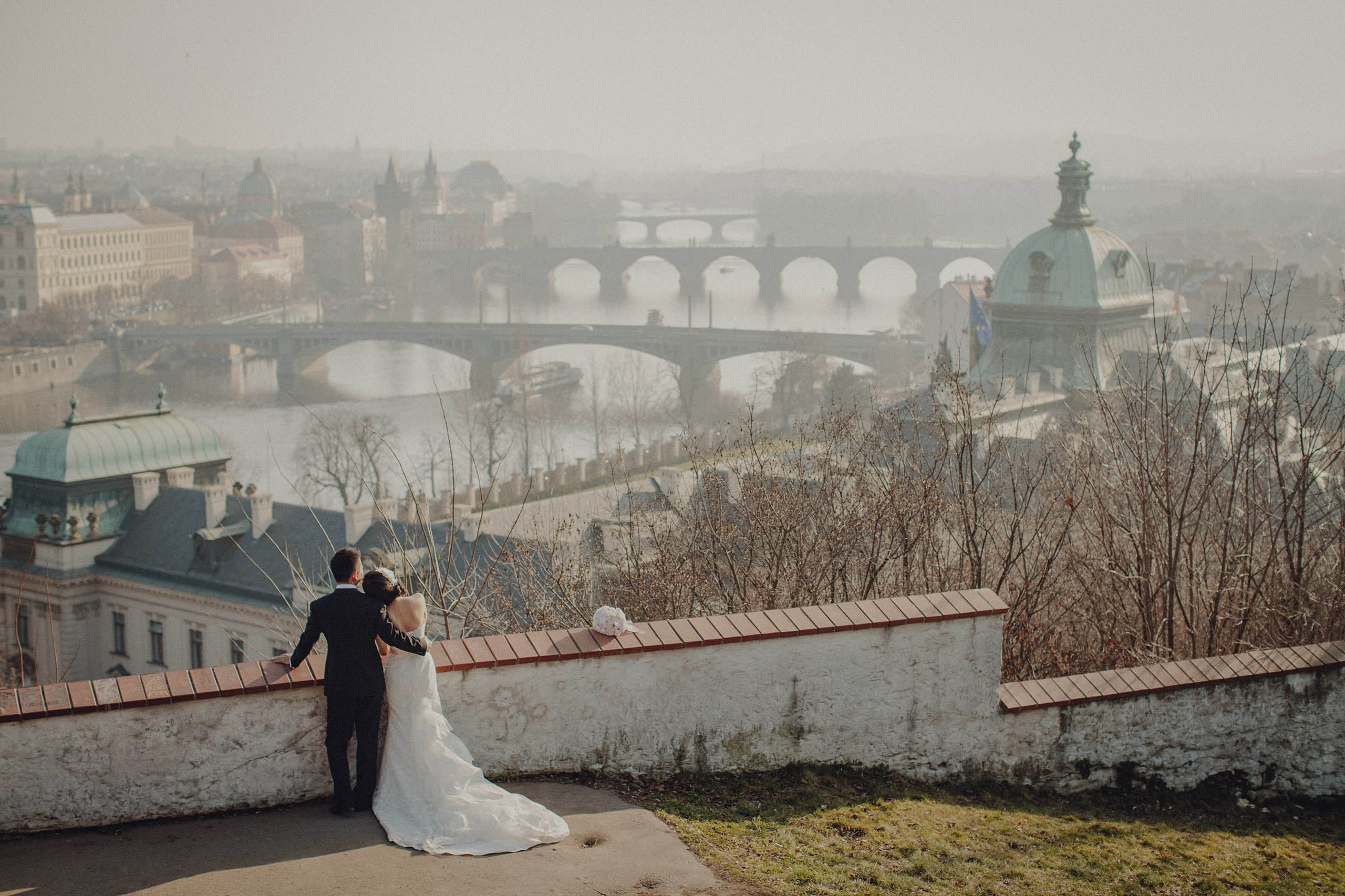 Asian newlyweds view the historic city of Prague as a foggy mist shrouds the city