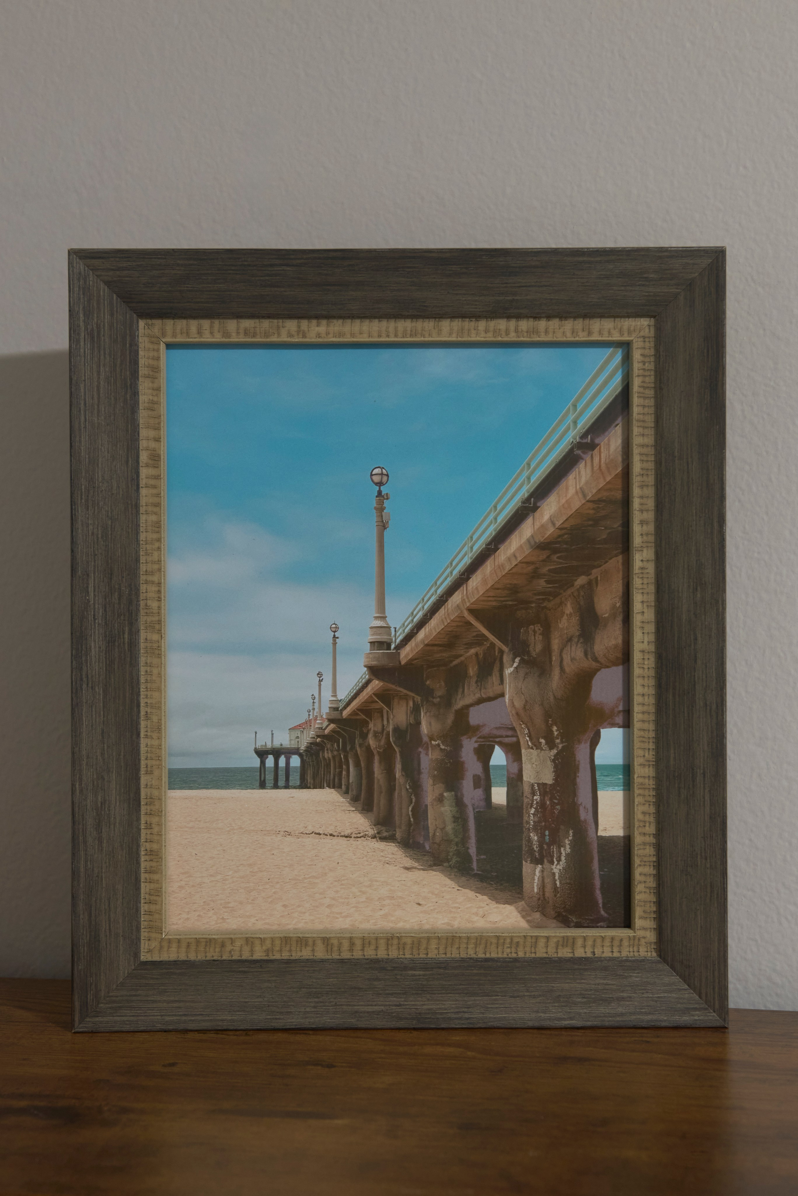 A framed photograph of the Manhattan Beach lifeguard tower under a soft cloudy sky