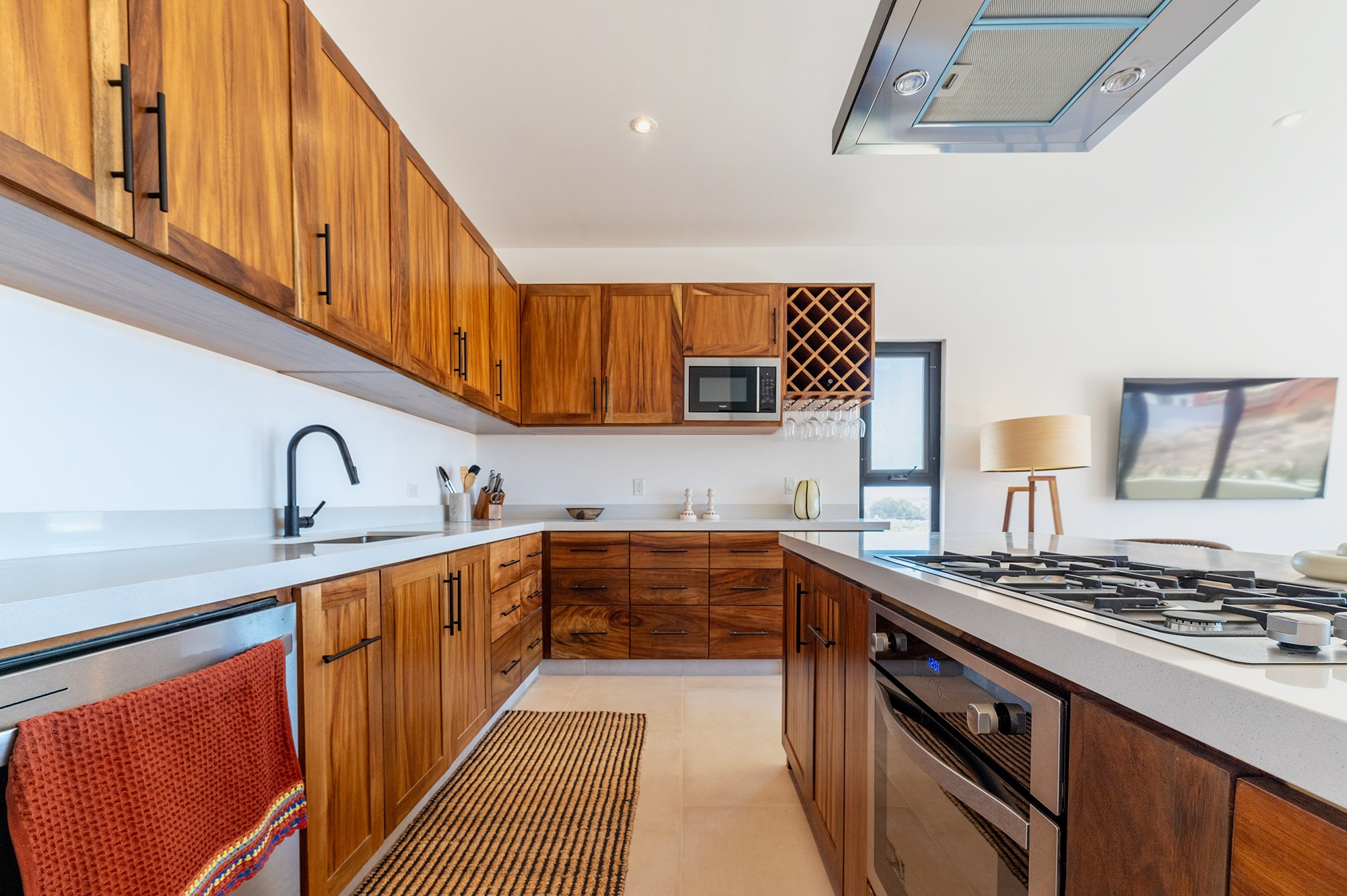 Modern kitchen interior in Los Cabos – white walls and wooden cabinets with stove and hood, professional real estate photography