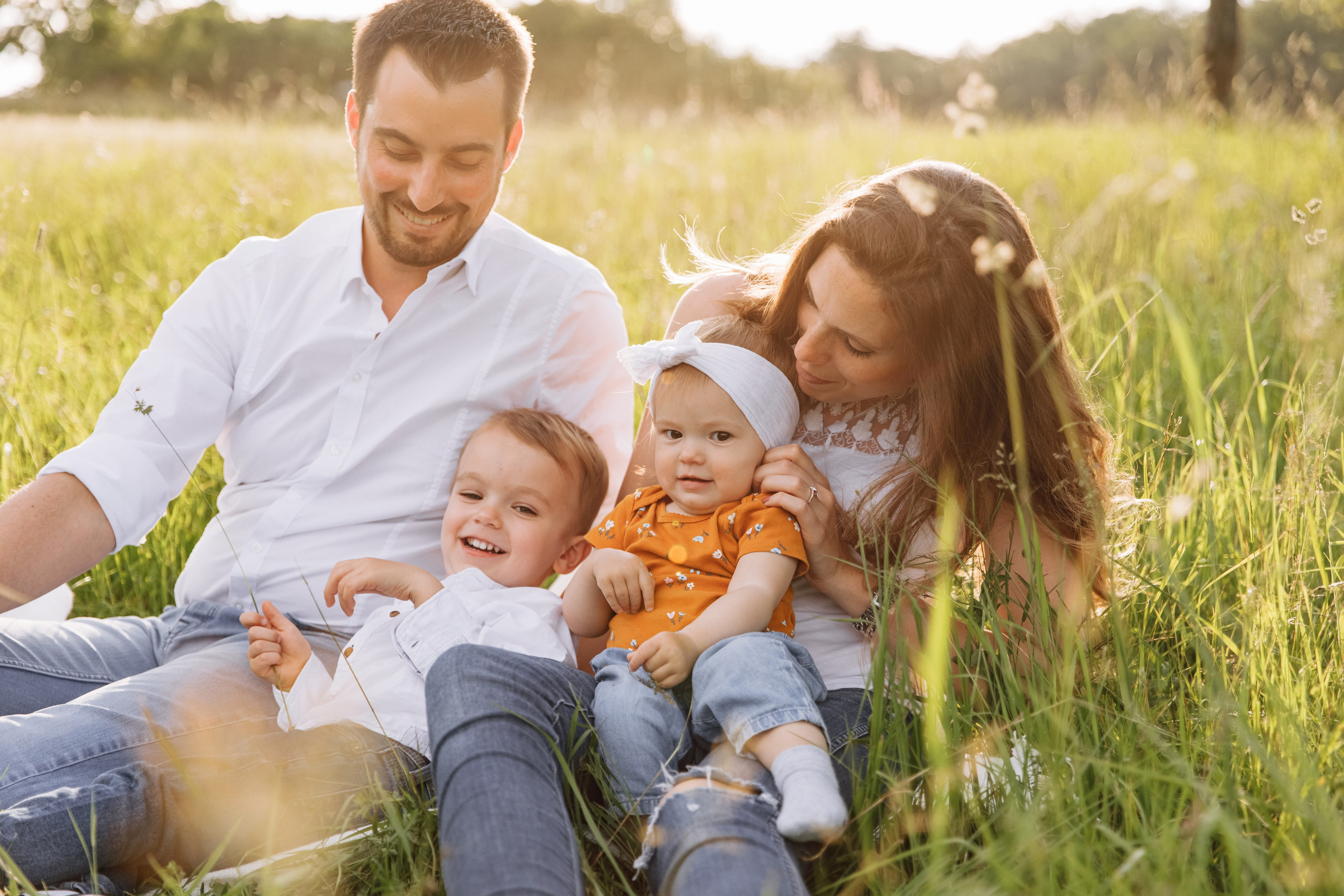 Familie sitzt auf einer Wiese während eines sommerlichen Fotoshootings.
