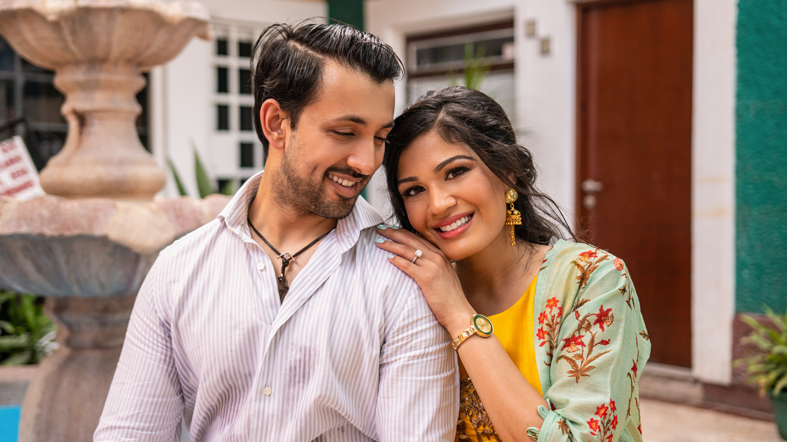 Romantic moment of a couple framed by palm leaves and colorful walls in Cancún, taken by a storytelling Mexico-based photographer