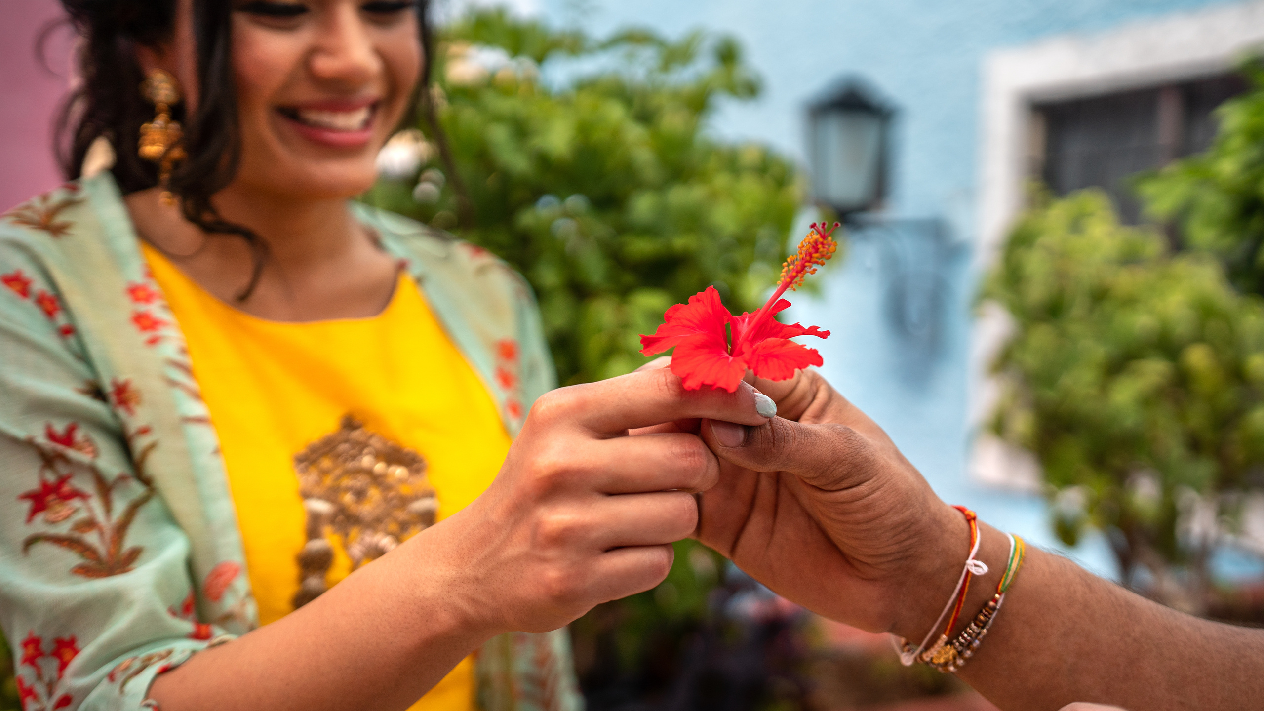 Stylish duo holding hands in front of a bold turquoise Cancún wall during a cultural couple photo shoot in Mexico.
