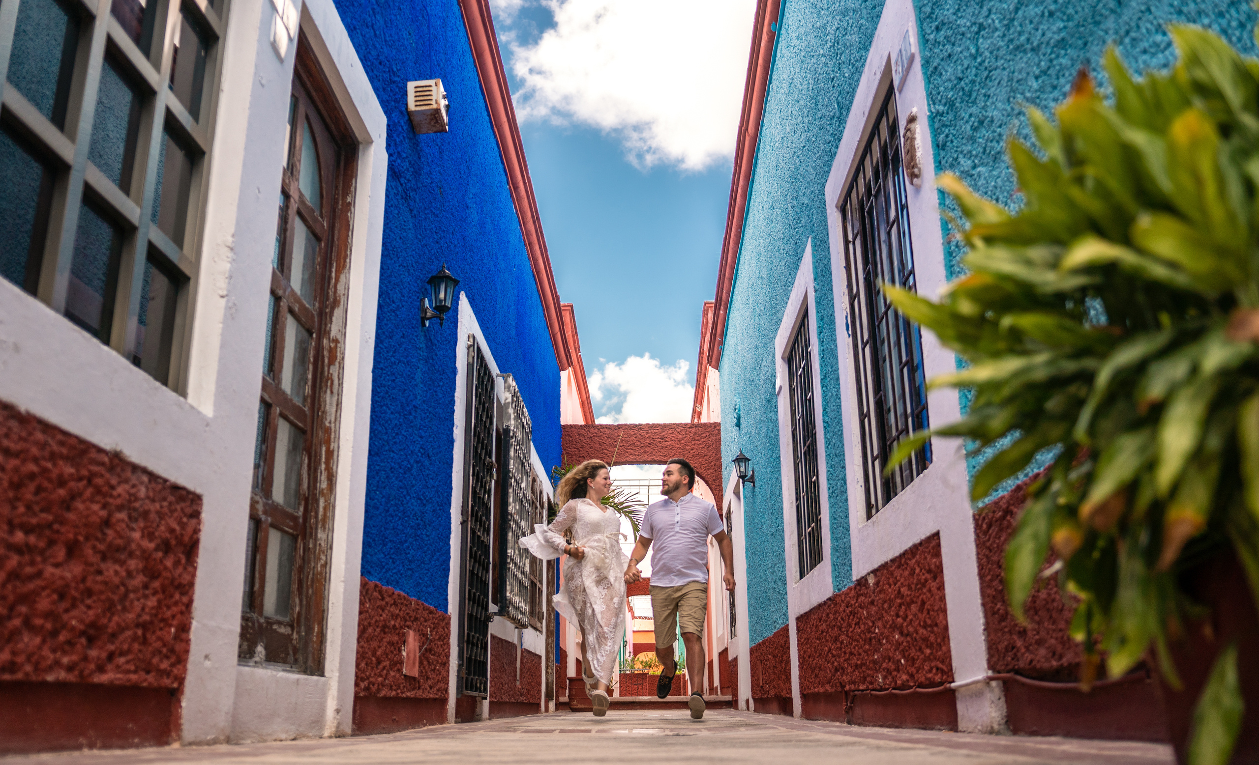 Engaged couple enjoying a spontaneous photo session with colorful colonial facades in the heart of Cancún.