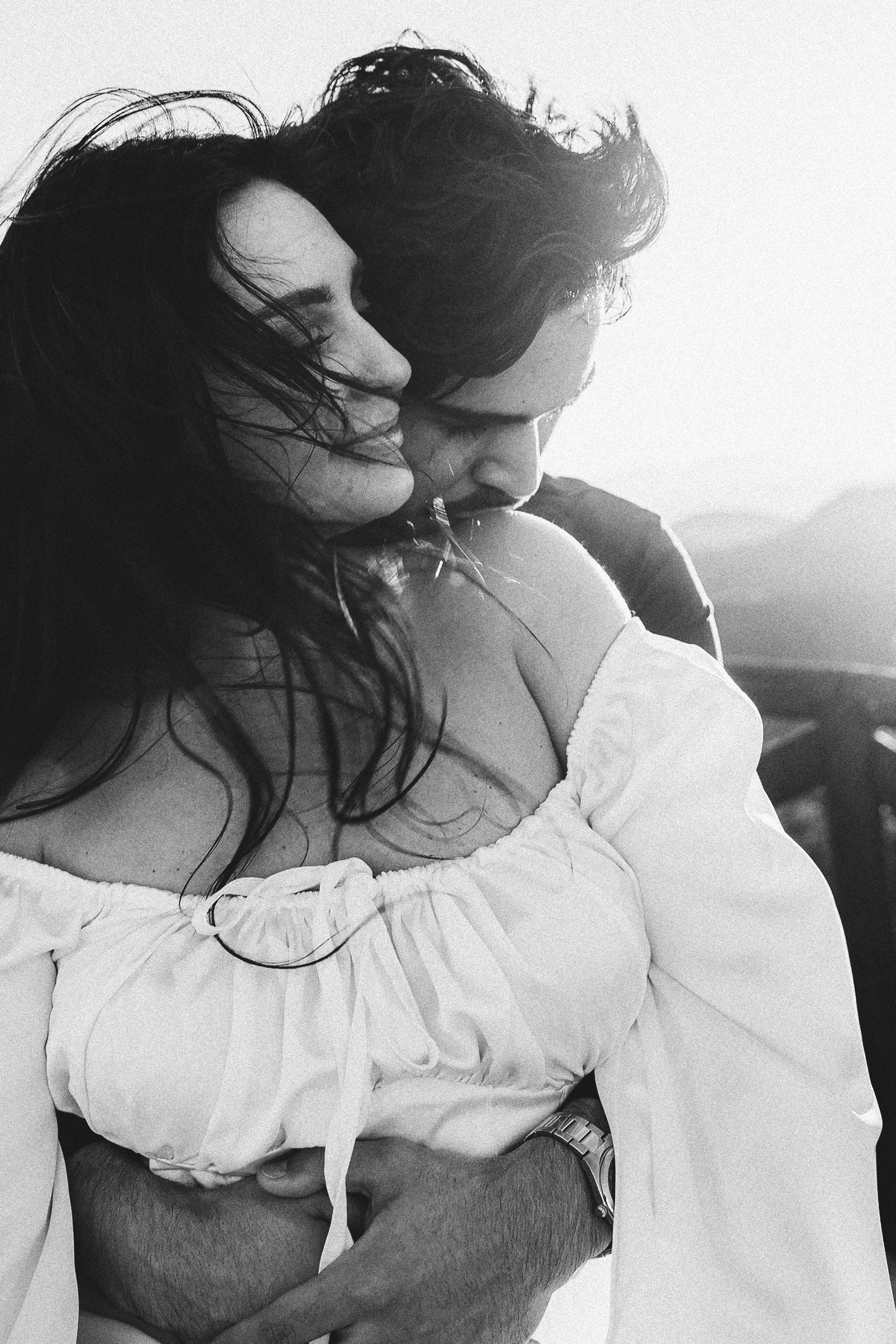 Romantic black and white portrait of a couple embracing at sunset, captured in a natural documentary style by a wedding photographer in Spain, highlighting intimacy and authentic emotion.