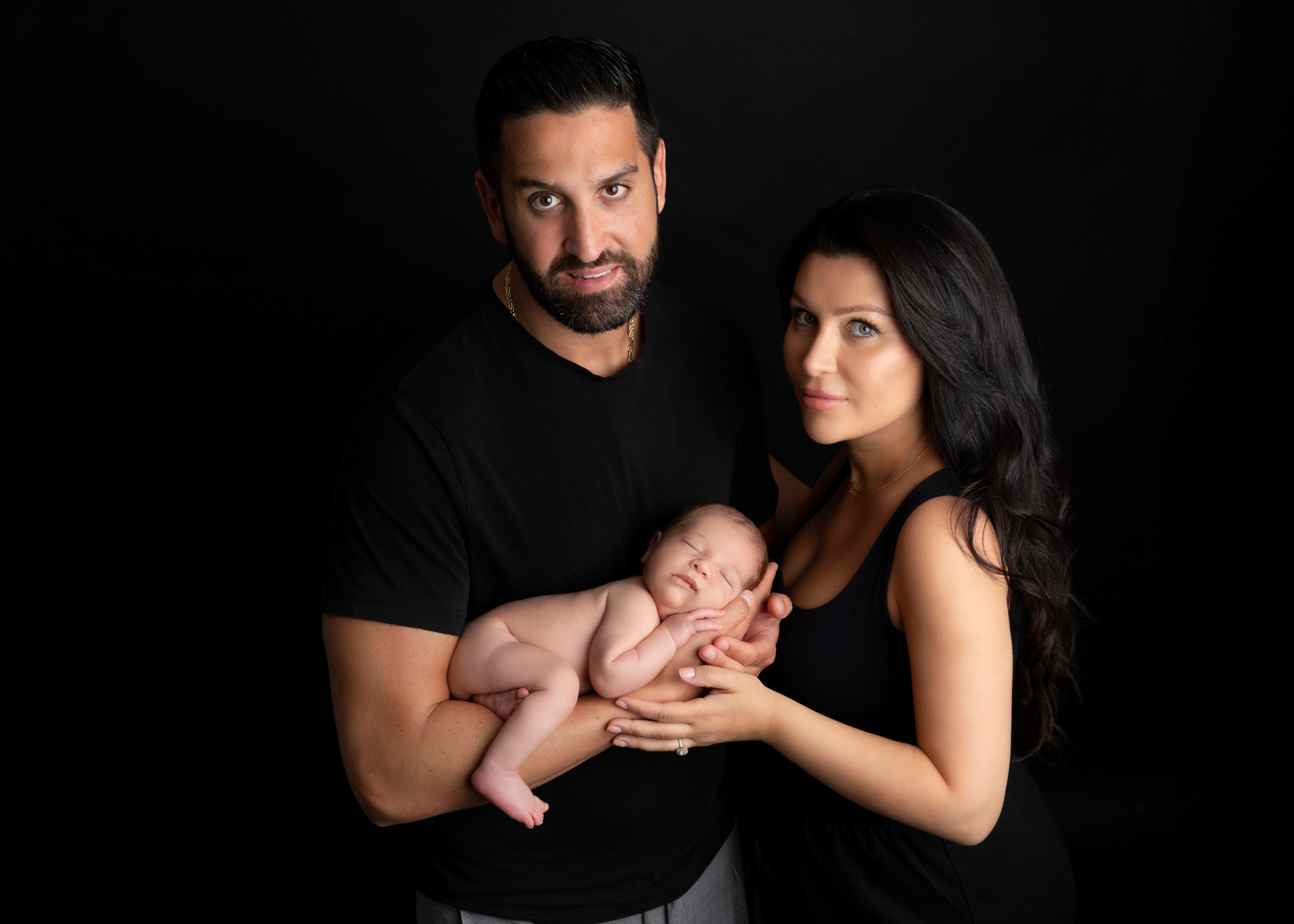 Pappa håller sin nyfödda bebis i famnen, ett fotografi från fototillfället fyllt av kärlek och stolthet.