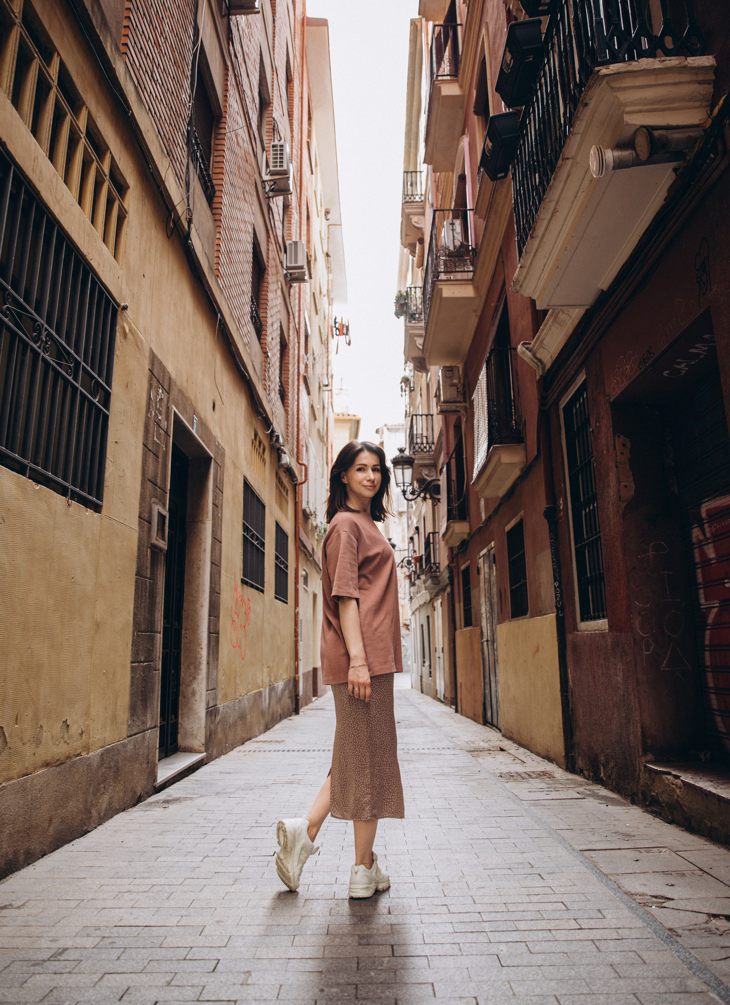 Очаровательный портрет женщины, идущей по узкой исторической улице в Мадриде, Испания — передаёт городскую элегантность и подлинную атмосферу, идеально подходит для портретных фотосессий в Мадриде и центральной Испании.