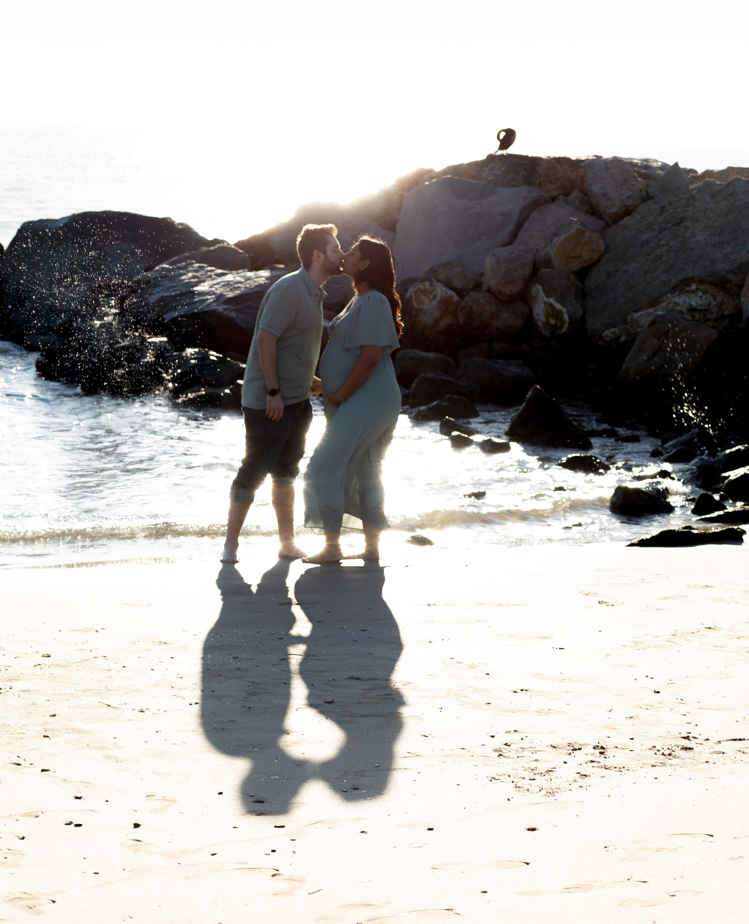 Sesión de maternidad romántica en la playa de Valencia, España — pareja embarazada compartiendo un beso al atardecer con sus sombras reflejadas en la arena. Un momento perfecto para quienes desean sesiones de embarazo íntimas y emocionales en Valencia y en localidades costeras de España.