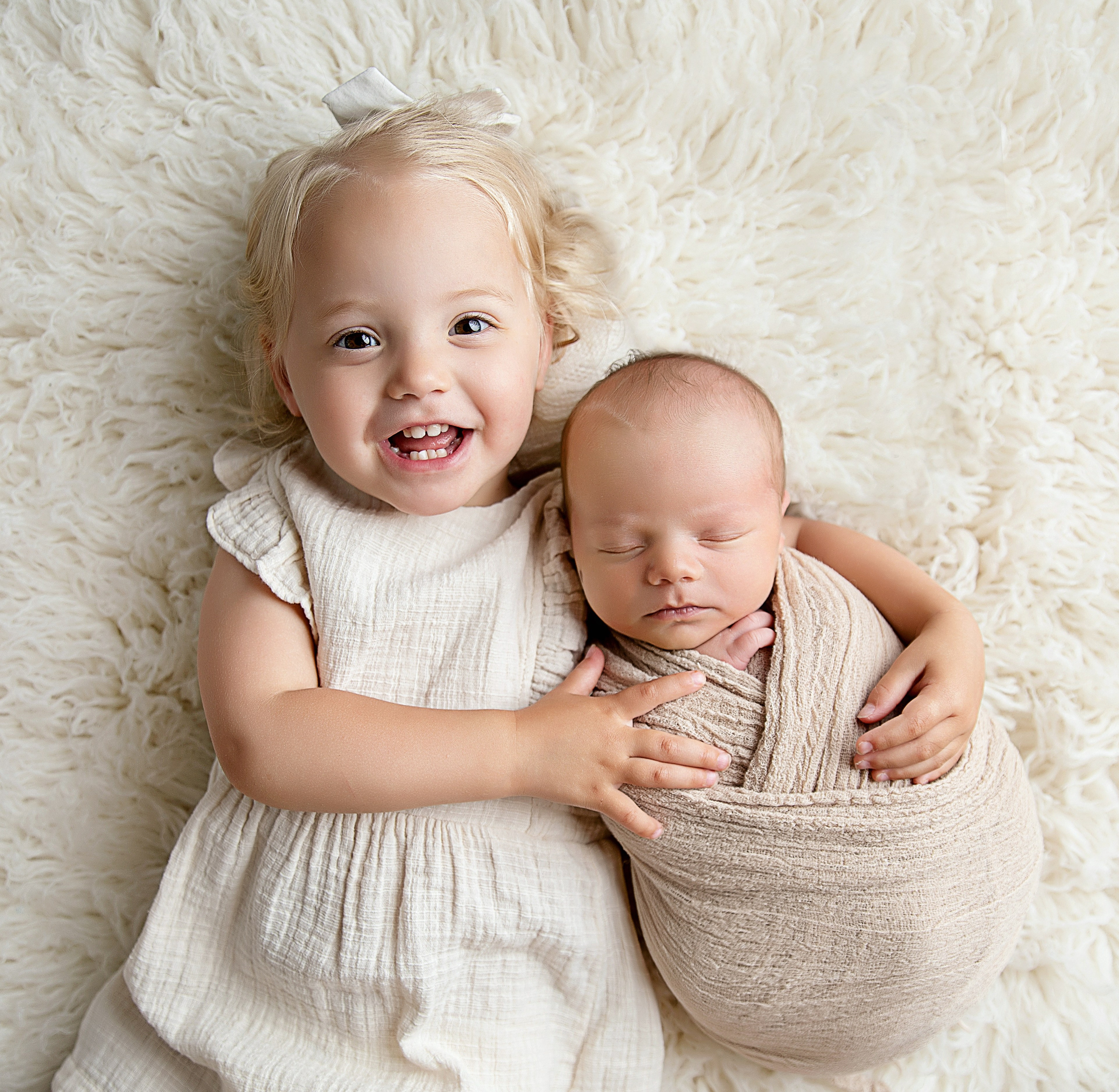 "Ett äldre syskon som sitter försiktigt bredvid sin nyfödda bror eller syster. Denna bild fångar den ömma och beskyddande relationen mellan syskonen och är idealisk för nyfödda fotograferingar."