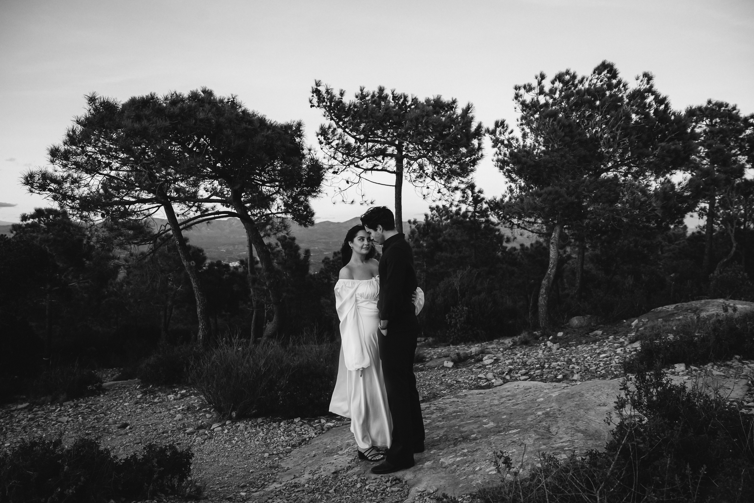 Bride and groom standing together among pine trees during an intimate mountain elopement in Barcelona, Spain. This natural destination wedding portrait captures the quiet romance of a private ceremony in nature.