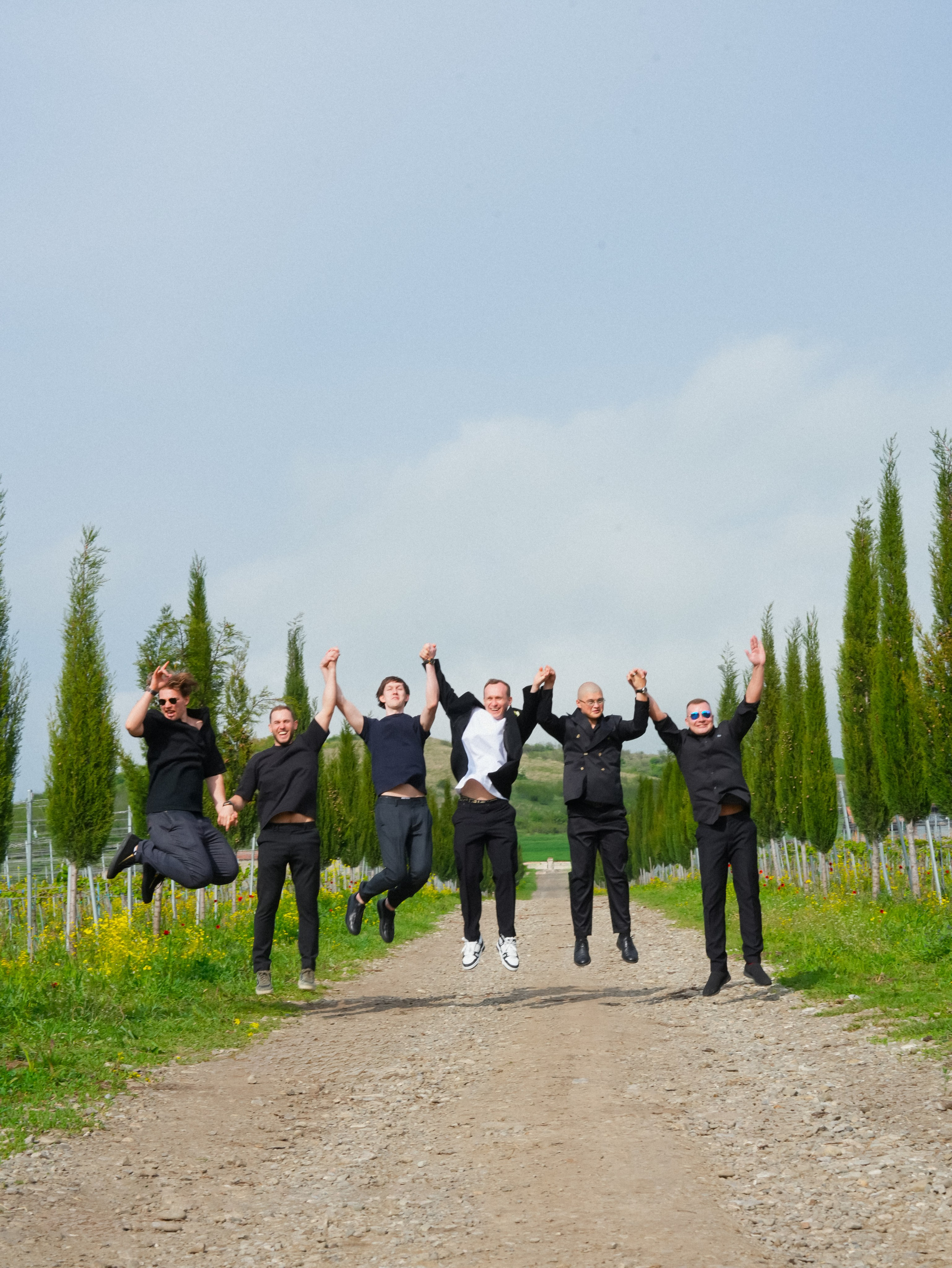 Friends jumping on road in vineyard landscape