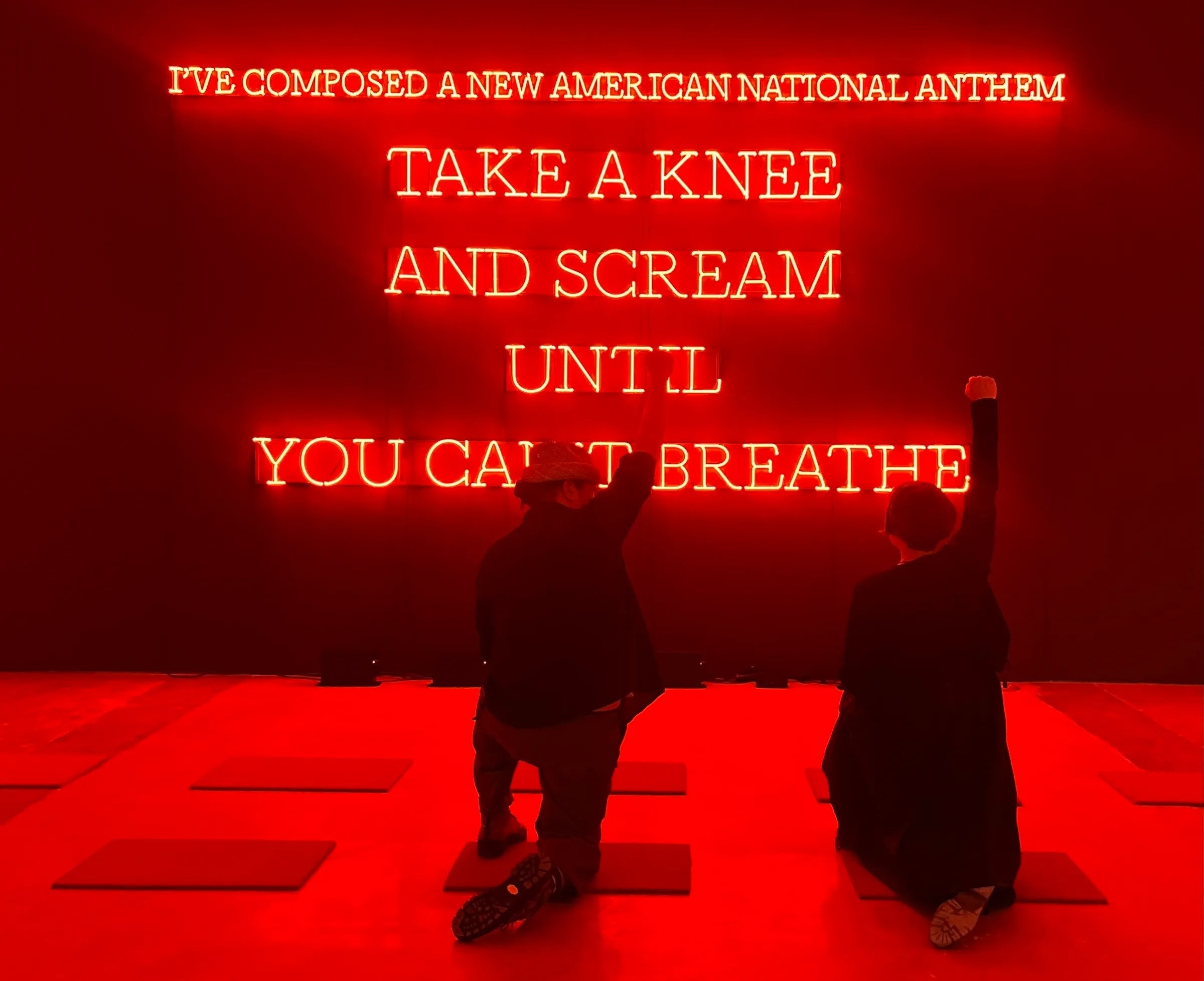 Неоновая инсталляция Николаса Галанина «Neon American Anthem (red)» (2023), выставленная в SITE Santa Fe, состоит из красного неонового текста на чёрной стене с надписью: «I’ve composed a new American national anthem: take a knee and scream until you can’t breathe», окружённого ковриками с ромашками, призывает к катарсическому протесту против системного насилия, воплощая анти-дизайн и цифровой брутализм через грубую, минималистичную эстетику. Николас Галанин (Nicholas Galanin, род. 1979, Ситка, Аляска, Tlingit/Unangax̂) — мультидисциплинарный художник, чья работа Neon American Anthem (red) (2023), созданная для выставки Interference Patterns в SITE Santa Fe, является частью трёхчастного проекта (white, red, blue). Инсталляция, выполненная с поддержкой Peter Blum Gallery и Becky Gochman, использует красный неон и текст, отсылающий к протестам Колина Каперника и убийствам Джорджа Флойда, Эрика Гарнера и других жертв полицейского насилия. Коврики с ромашками («Daisy Doormats»), символизирующие американскую субурбию, создают ироничный контраст с призывом к протесту. Работа соответствует эстетике анти-дизайна и брутализма, отвергая коммерческую полированность и подчёркивая «сырую» эмоциональность. Зрители «платят» участием (коленопреклонением и криком), а инсталляция «отдаёт» критику колониализма и капитализма, что перекликается с концепцией Transaction Art. 