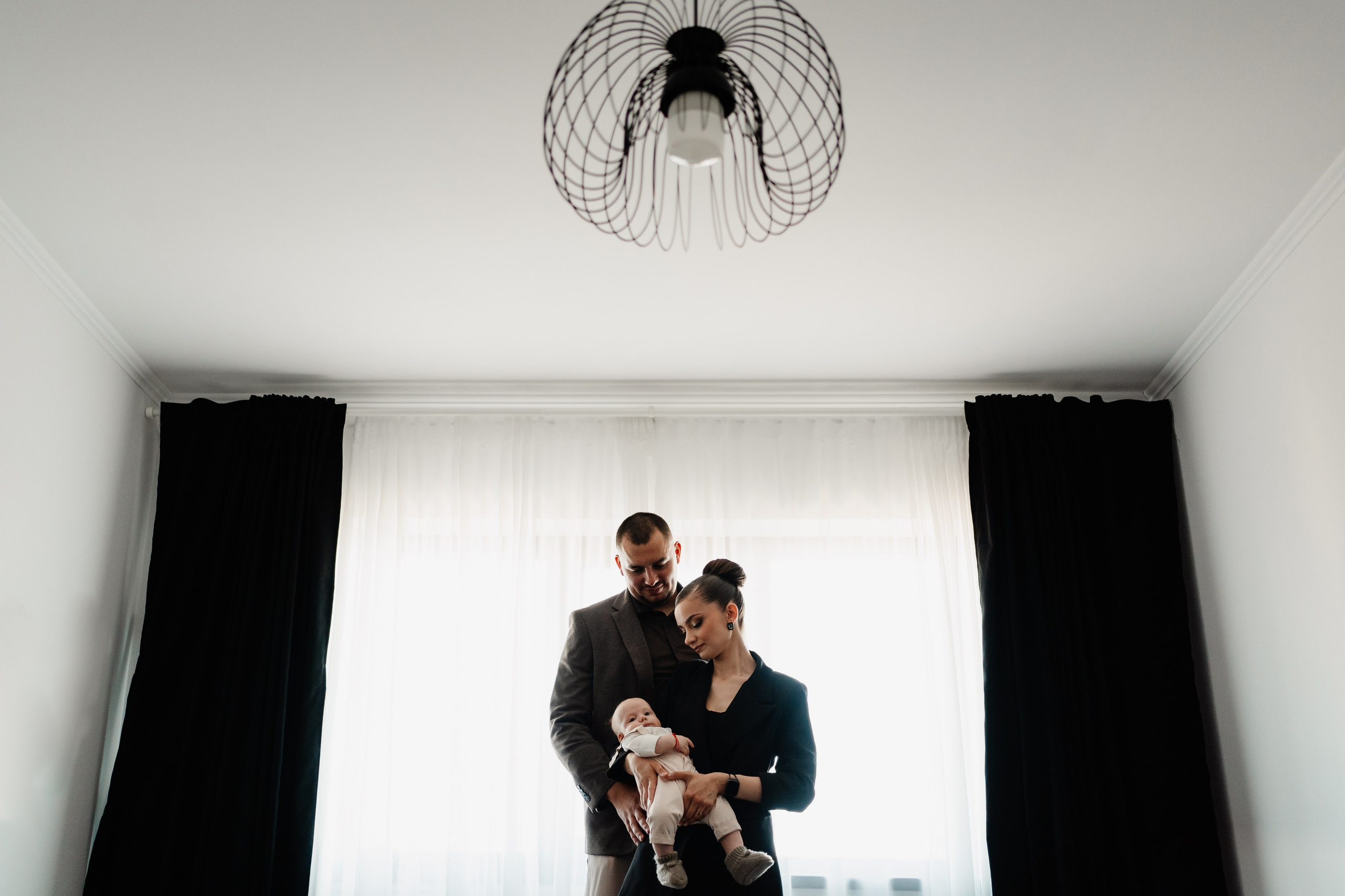 Instantaneu plin de tandrețe dintre părinți și bebeluș în ziua botezului, realizat în Craiova. Fotografie profesională de botez, capturând emoțiile autentice ale familiei într-un decor luminos și cald