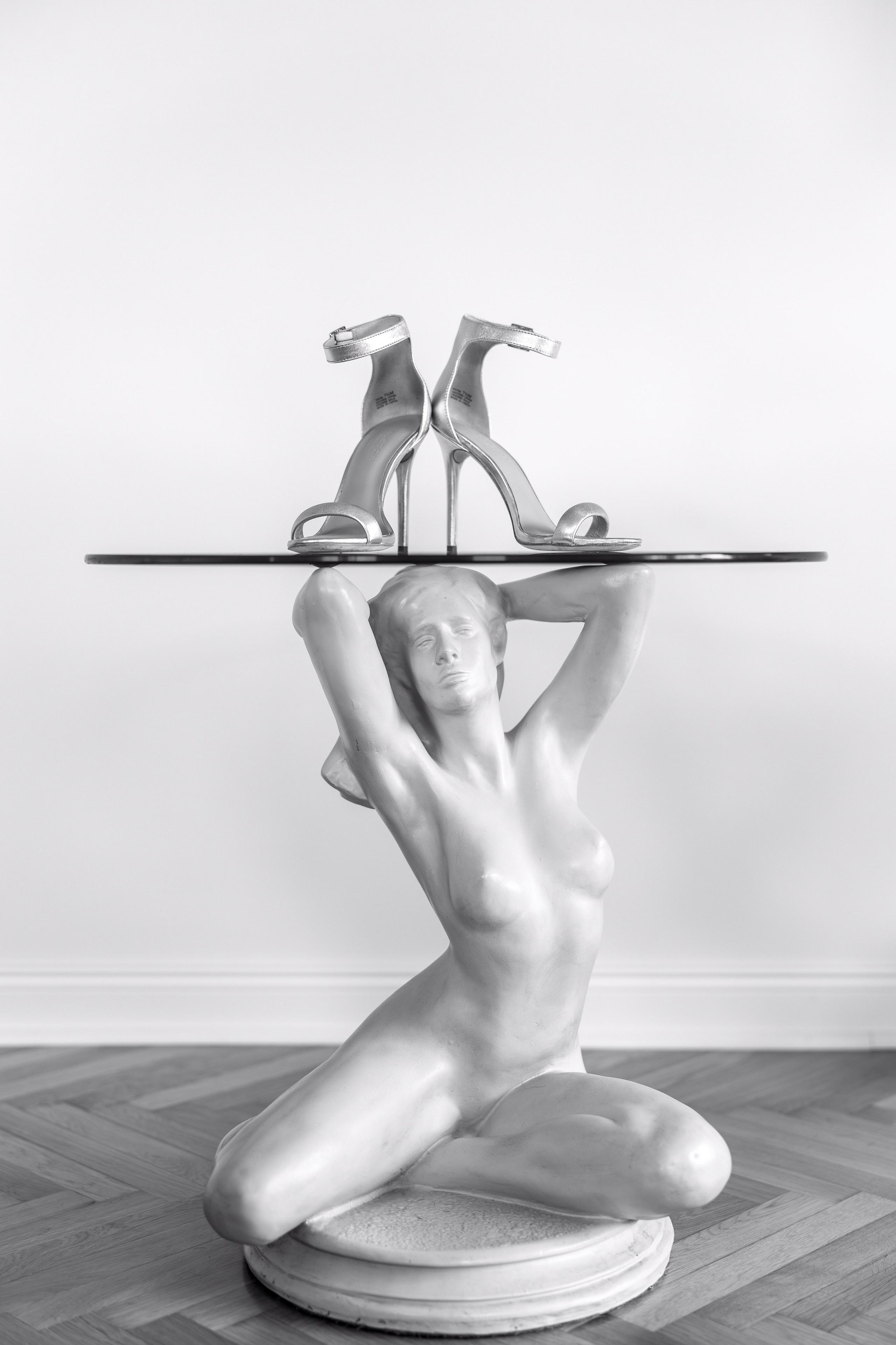 sto sa postoljem od statue i cipelama na stolu 