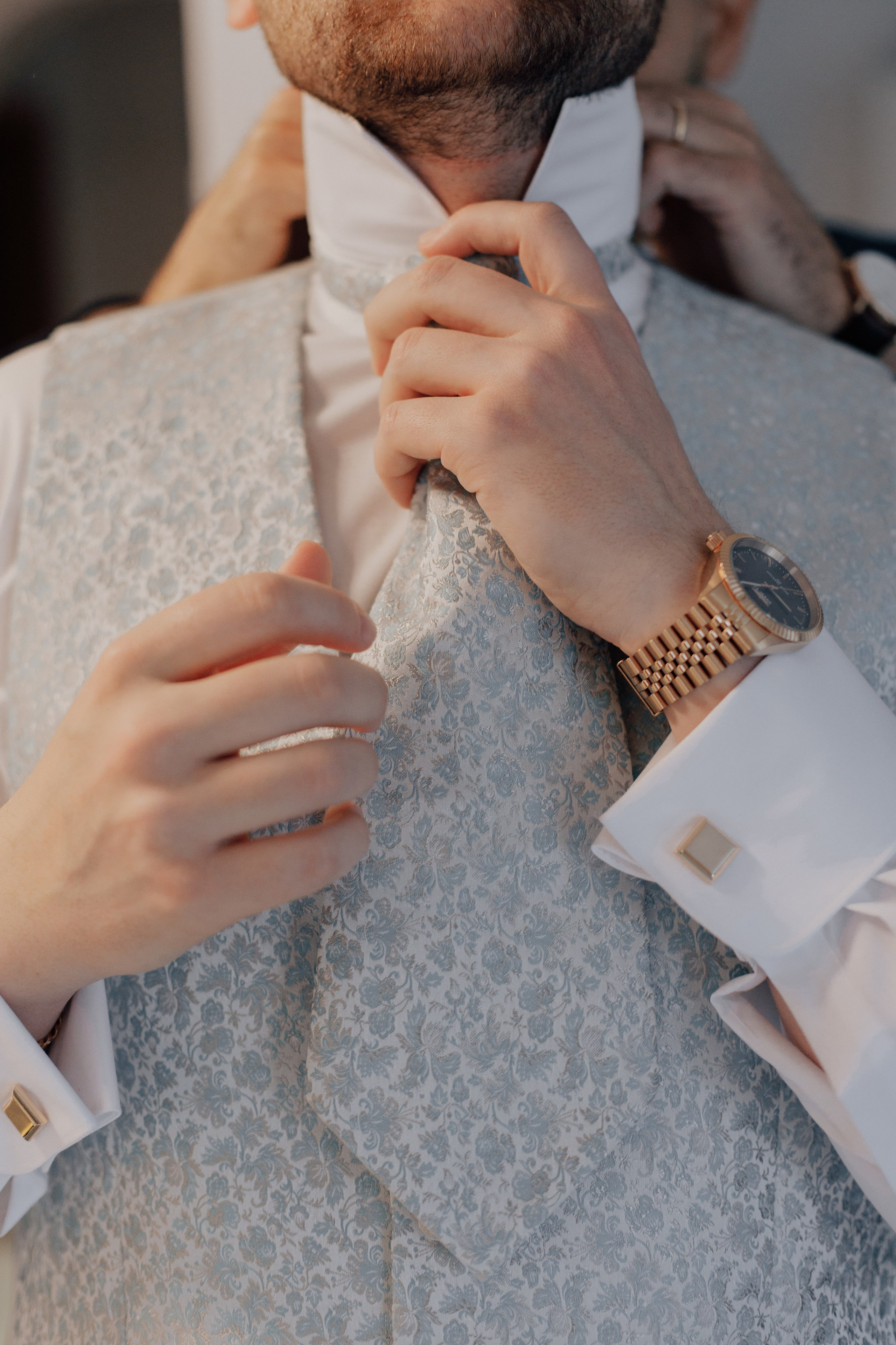 Die Hände des Bräutigams richten seinen Hochzeitskrawatte. 