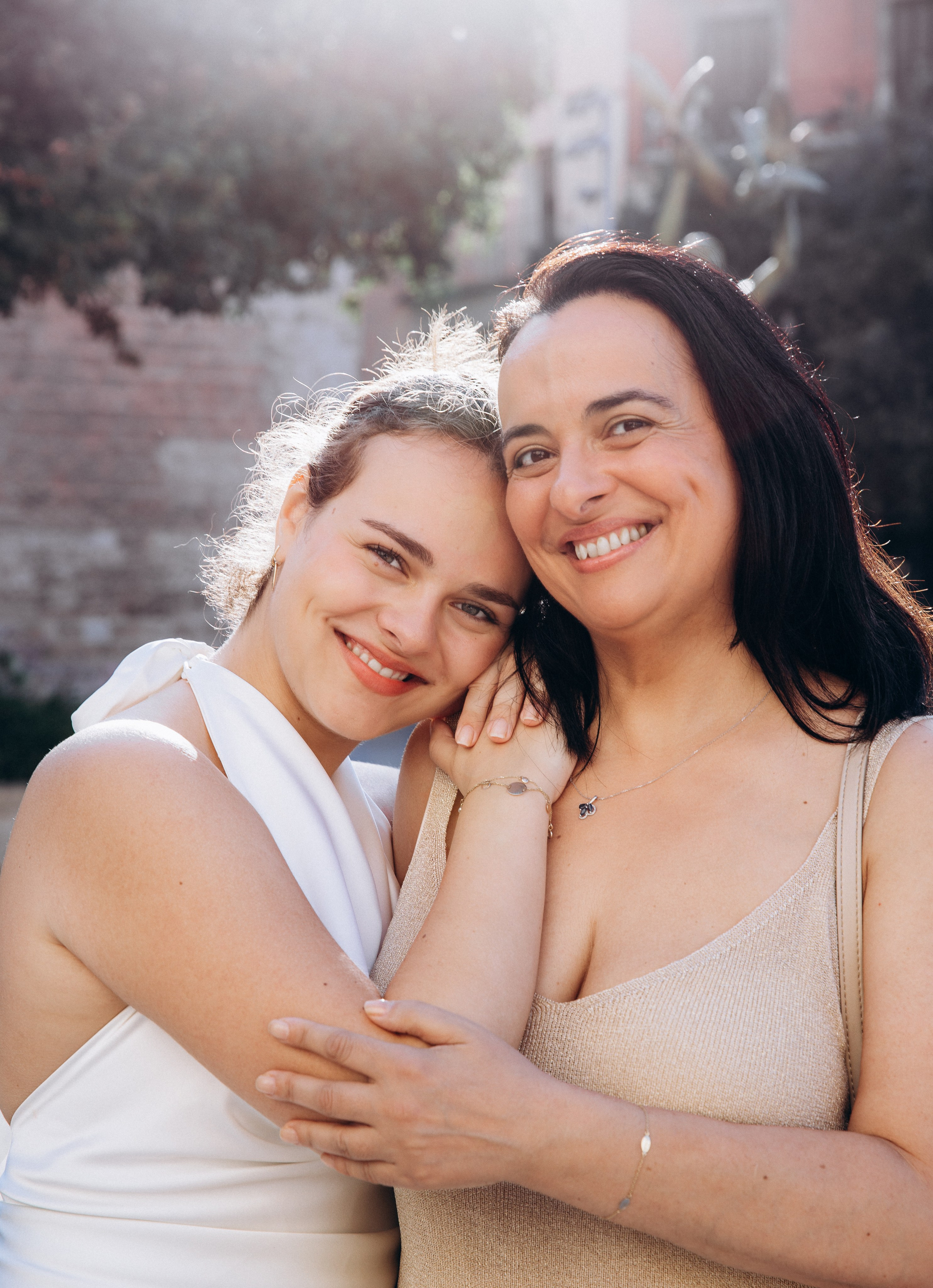 Conmovedor retrato de madre e hija en Madrid, España — fotografía natural al aire libre de una madre sonriente abrazando a su hija con luz suave, capturando alegría, amor y un profundo vínculo familiar. Perfecto para quienes buscan sesiones auténticas y emotivas en Madrid y toda España.
