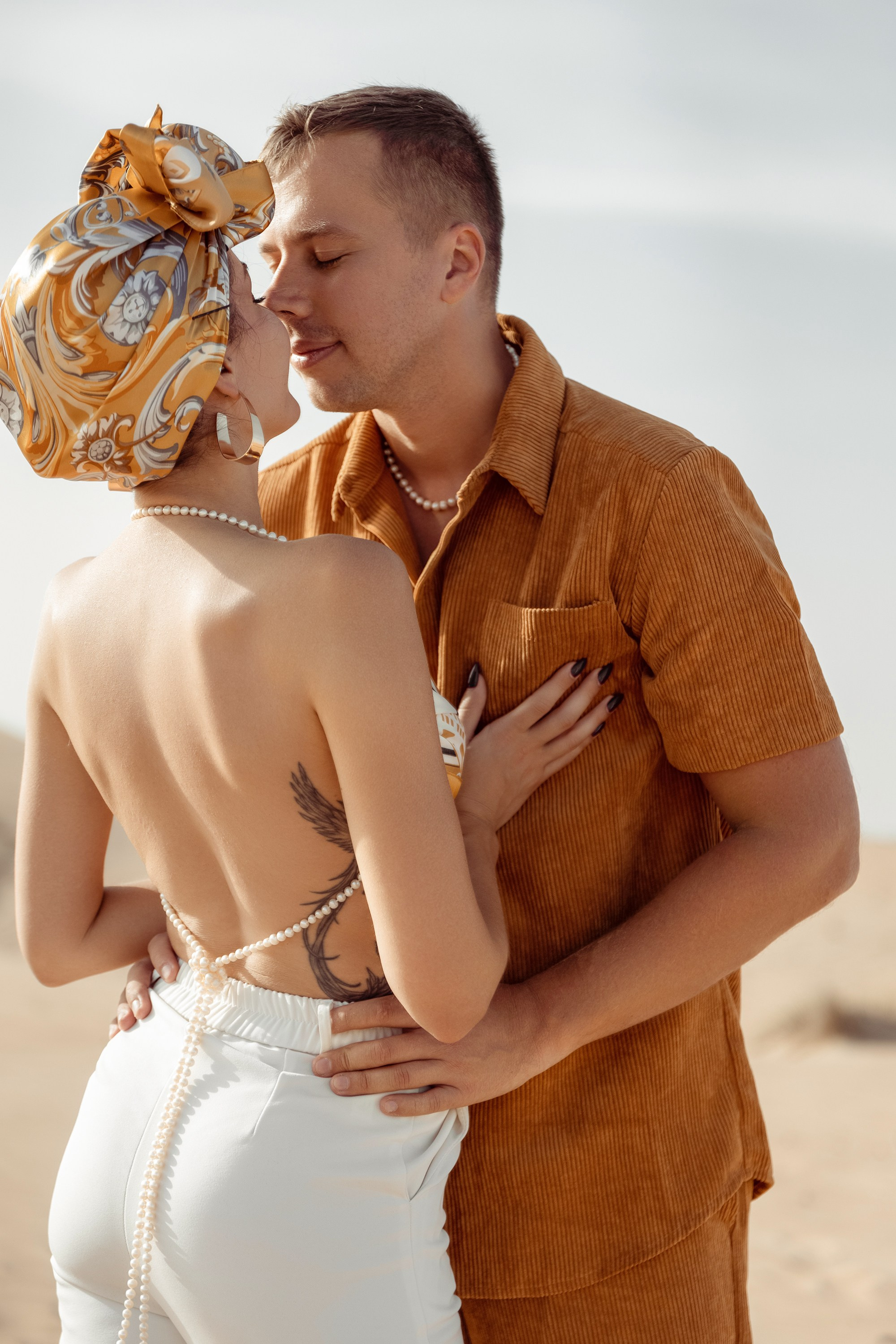 A romantic desert scene: a couple hugs, their silhouettes glowing under the warm sunset light. Dubai, United Arab Emirates