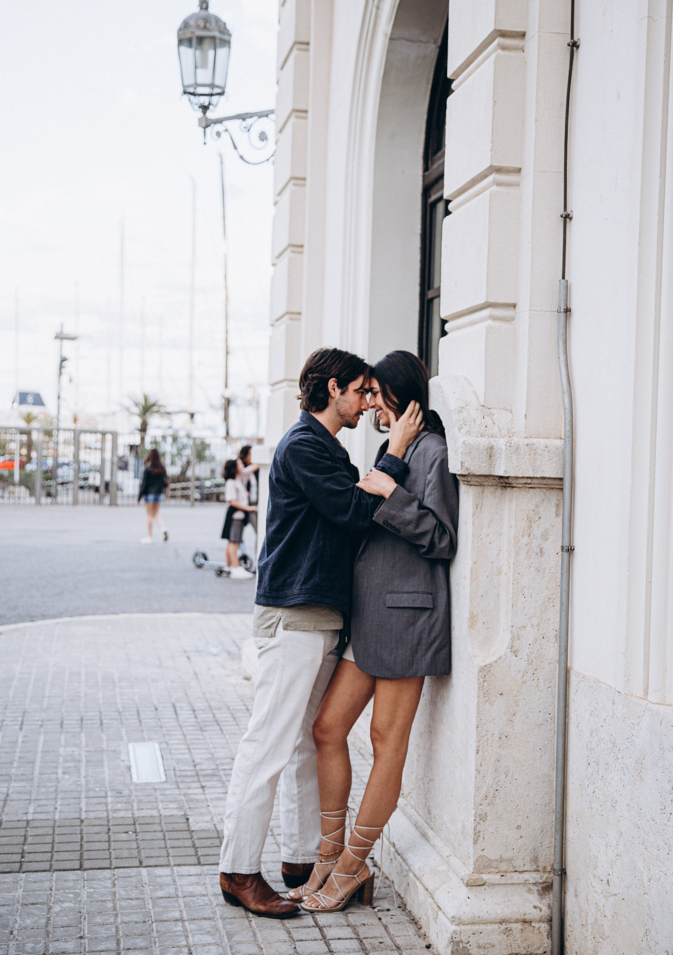 Romantic couple leaning close against a historic building in Madrid, Spain — capturing playful intimacy and genuine connection in an urban love story photoshoot, ideal for couples seeking natural and stylish photography in Madrid and Spain.