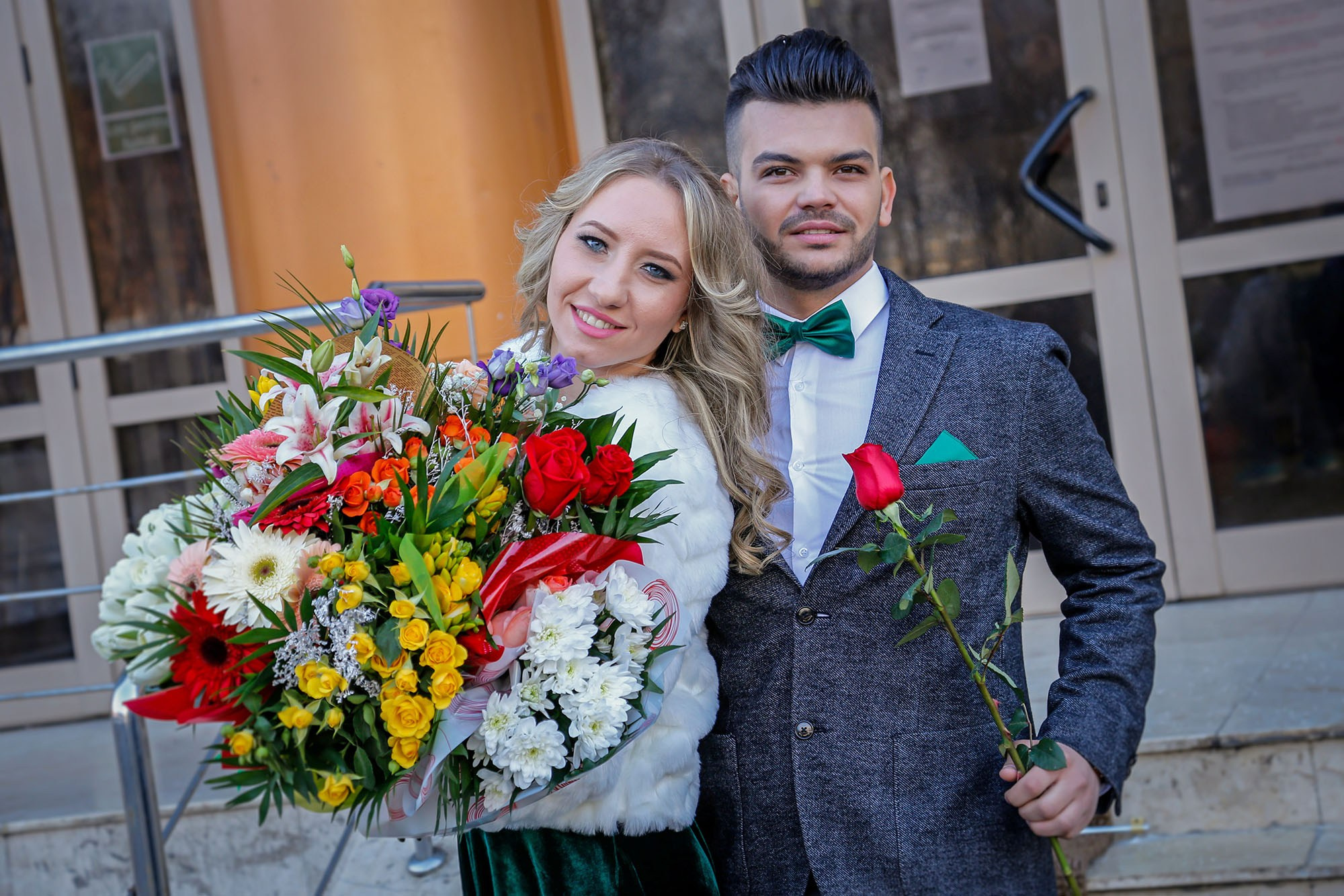 Close-up portrait of the smiling newlyweds, highlighting the elegant white tulip bouquet and winter wedding attire details.