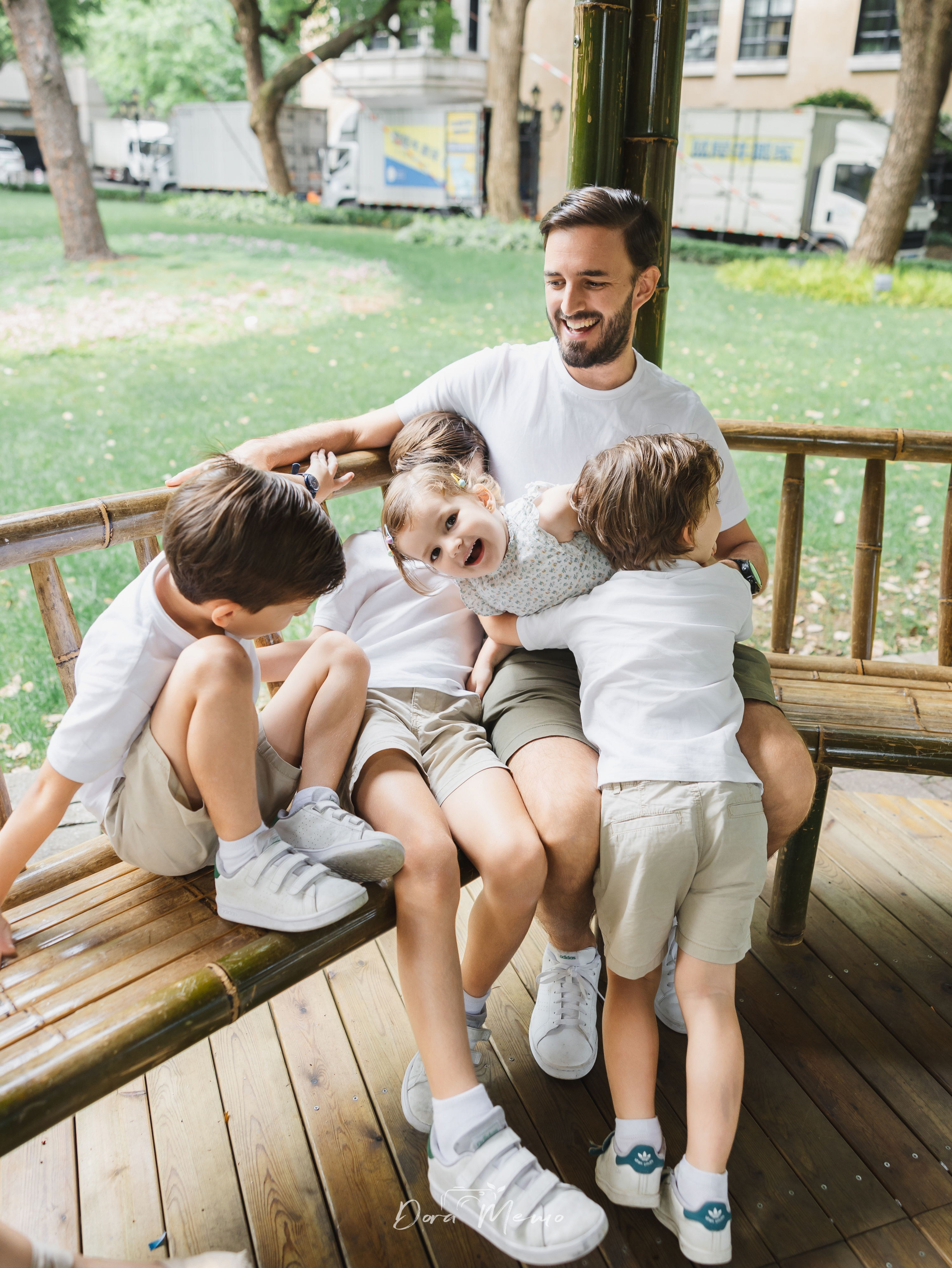 Dad with all four kids on a bench | Father sitting on a bench with his four children, candid family moment 