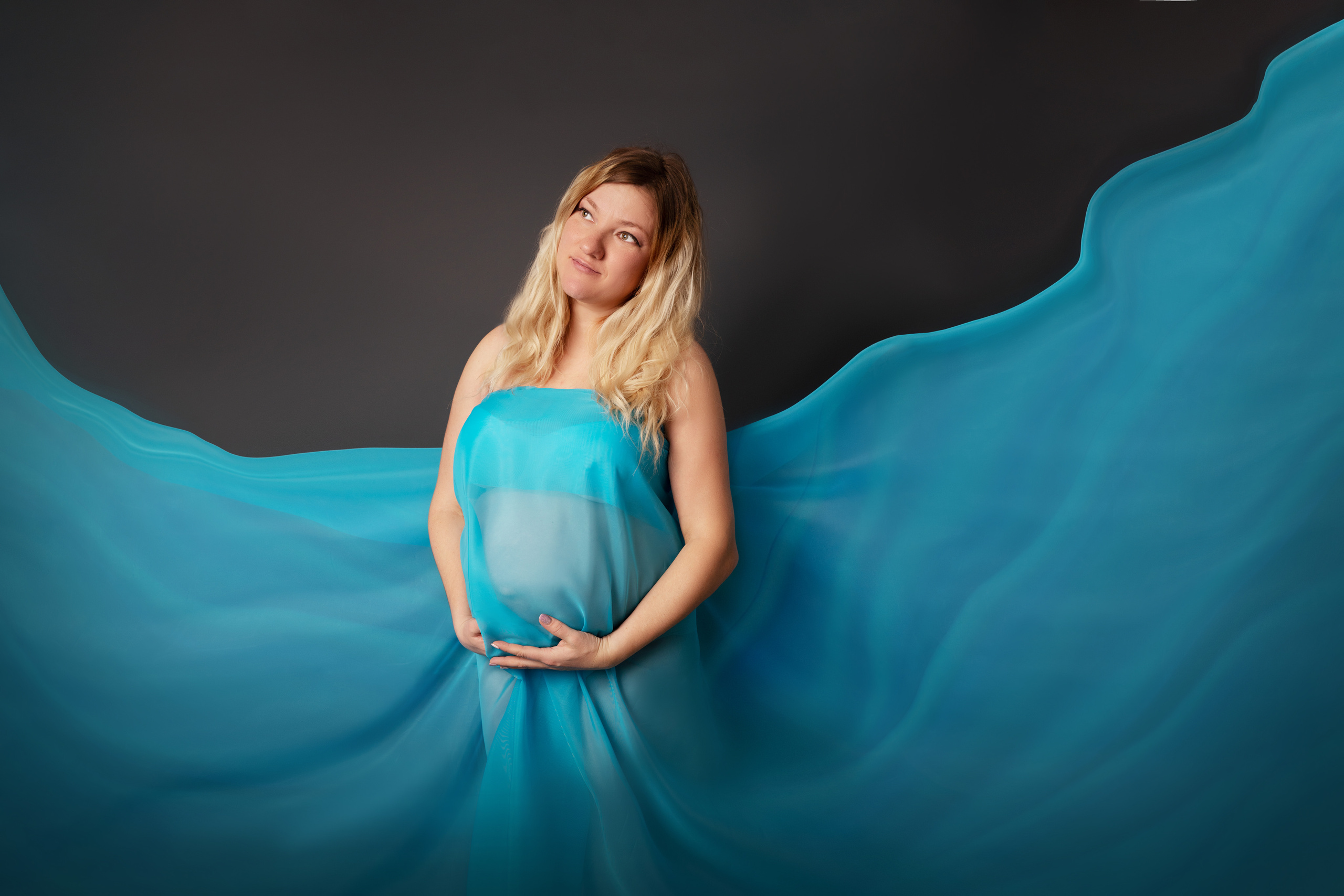 Schwangerschaftshooting im Studio im blauen Kleid