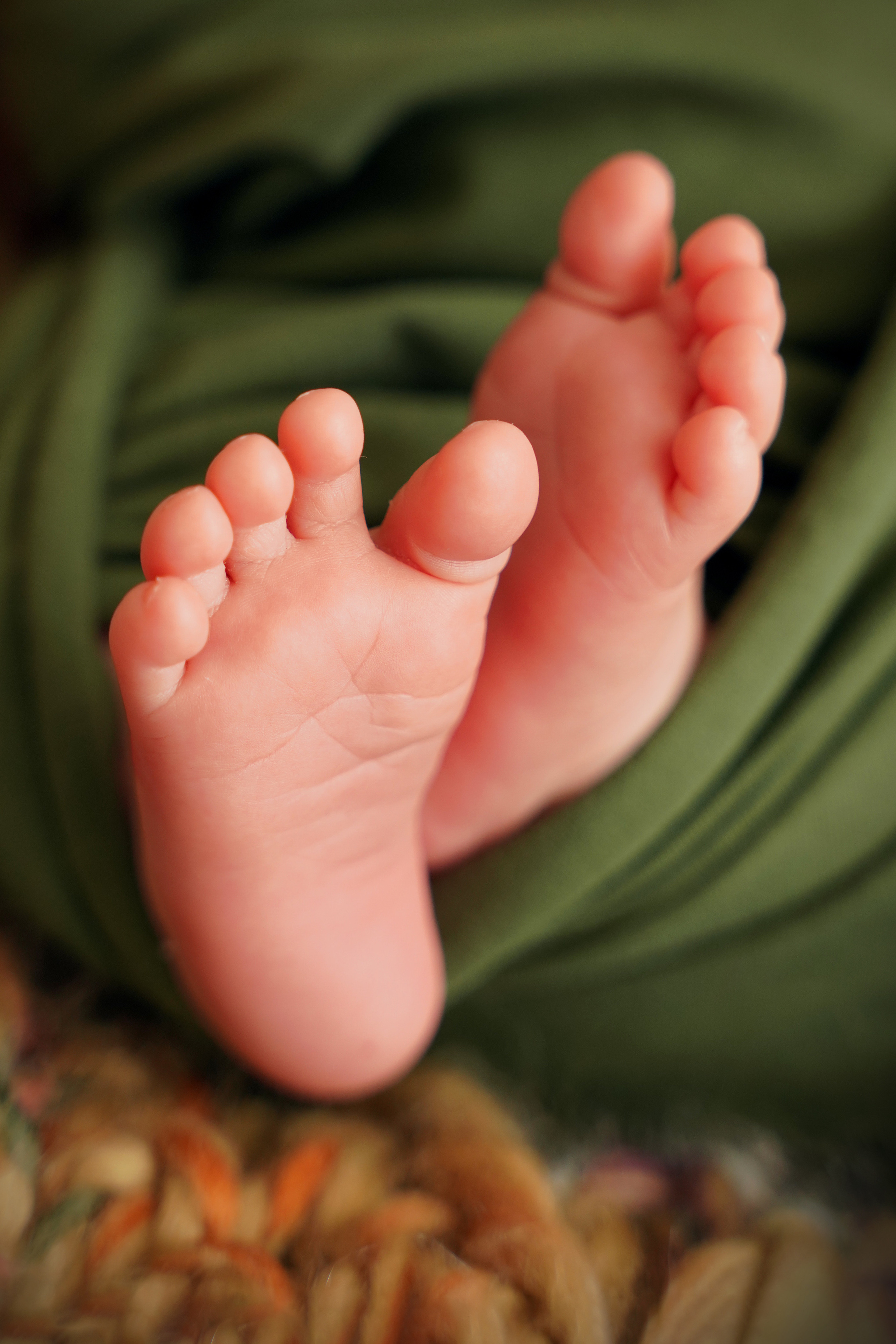 die Fersen eines Neugeborenen in einer grünen Windel